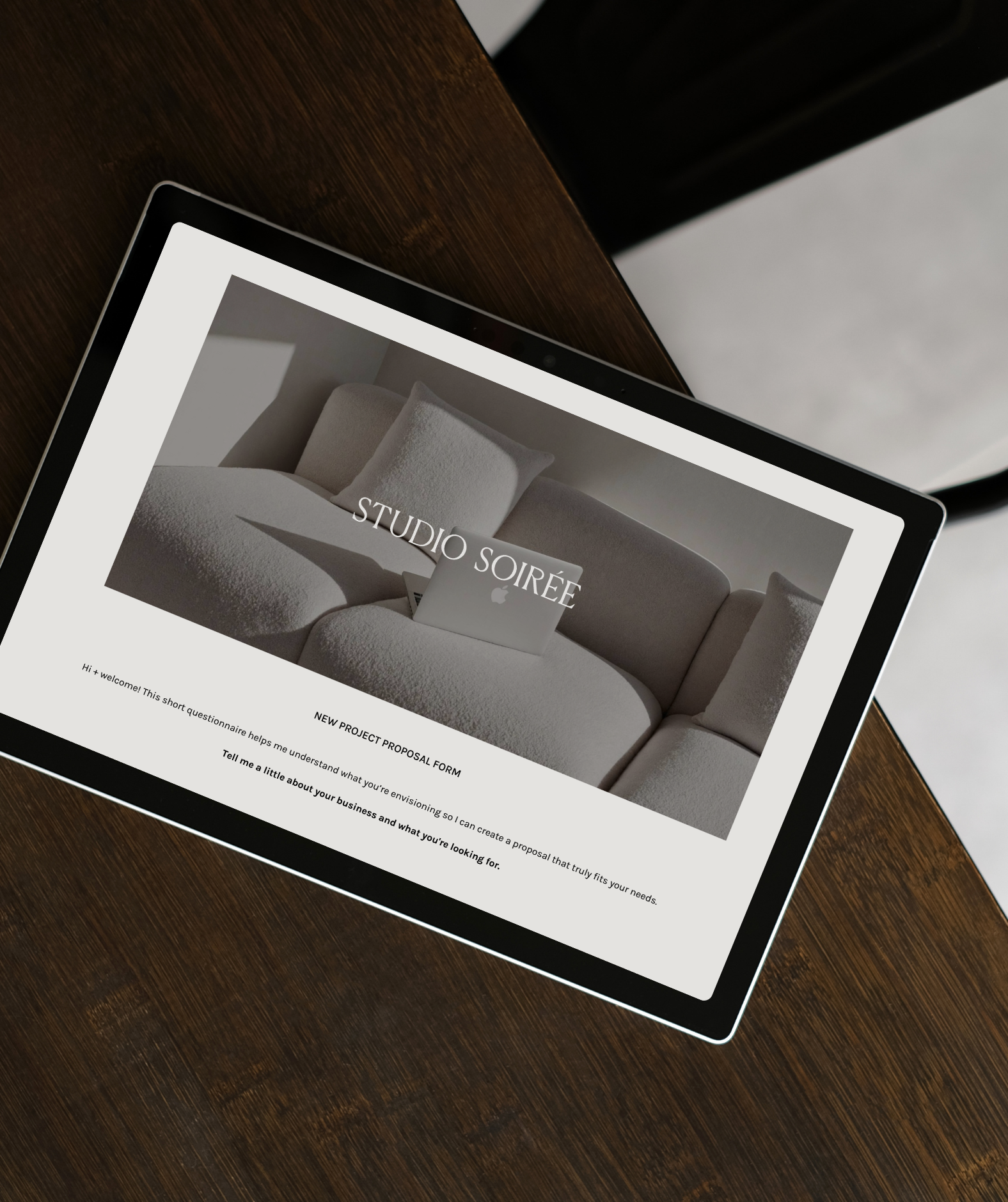 A tablet displaying a website called Studio Soirée with a homepage featuring a white sofa and pillow. The screen shows a project proposal form with text prompts.