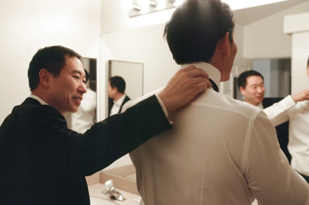 Groom getting ready with a friend adjusting his tie at Hummingbird Nest Ranch in Santa Susana, California, photographed on 35mm film.