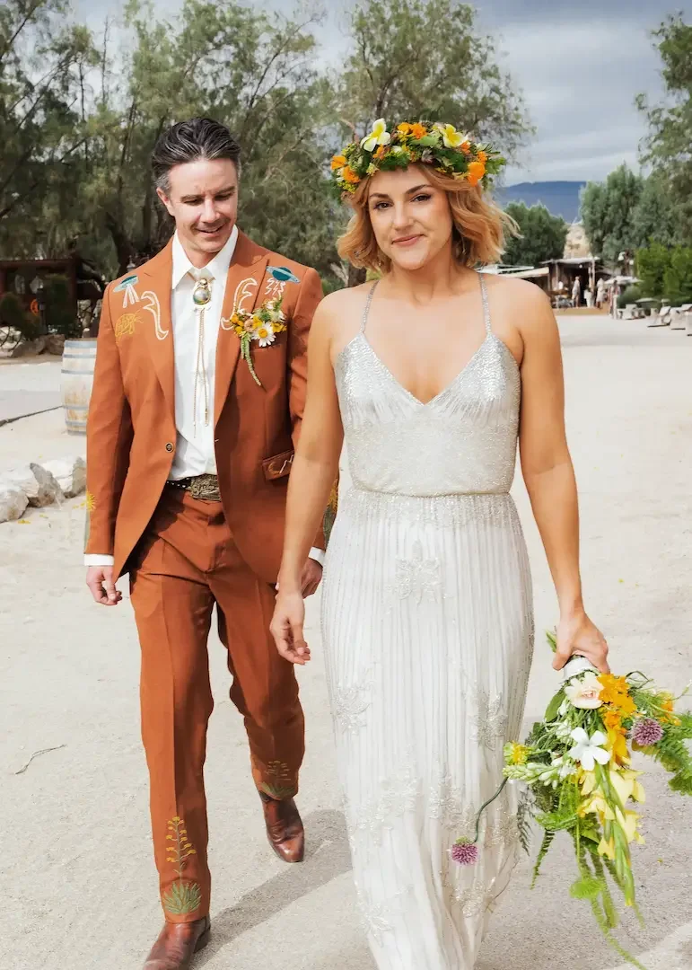 Palm Springs analog film wedding photo of bride and groom walking at The Lazy C Ranch during a space cowboy themed celebration.
