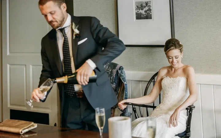Candid moment of bride and groom pouring champagne before Malibu beach wedding shot on 35mm film