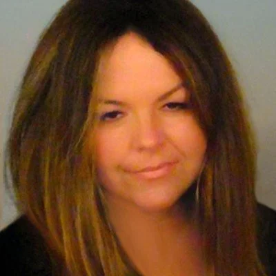 A woman with long, wavy brown hair and a slight smile.