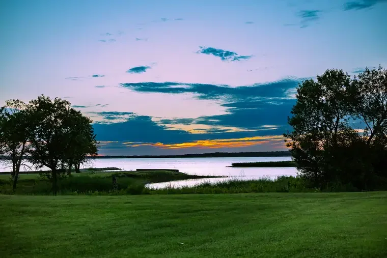 Sunset over a river with trees on the grassy shoreline
