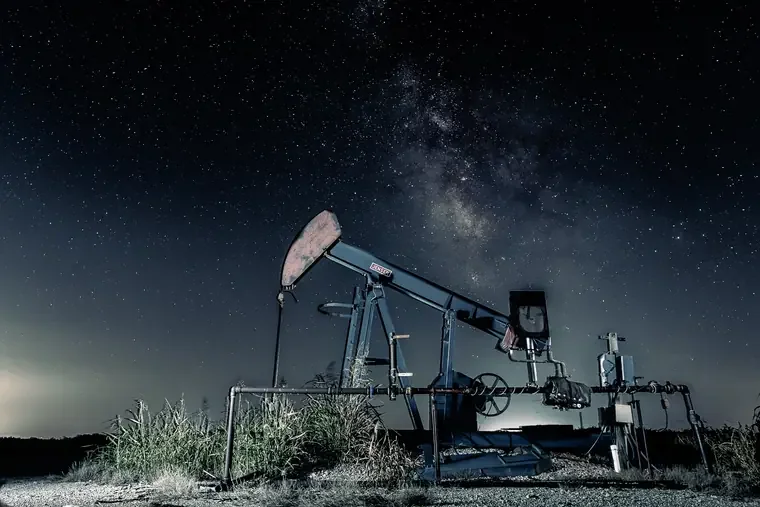 An oil pumpjack operating at night under a starry sky with the Milky Way visible