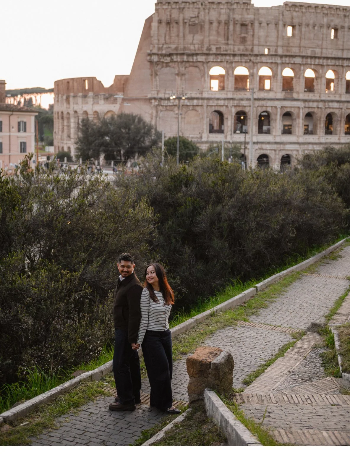 couple walking in Rome near Colosseum romantic photoshoot cobblestone street Italy