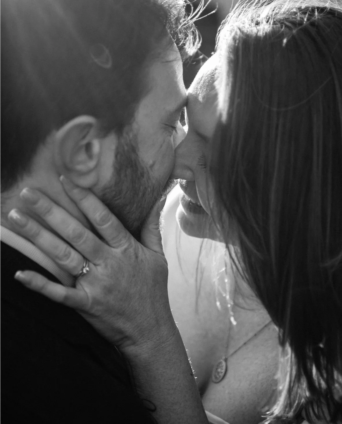 A black and white photo of a couple kissing intimately, with the woman holding the man's face gently and the man's eyes closed.