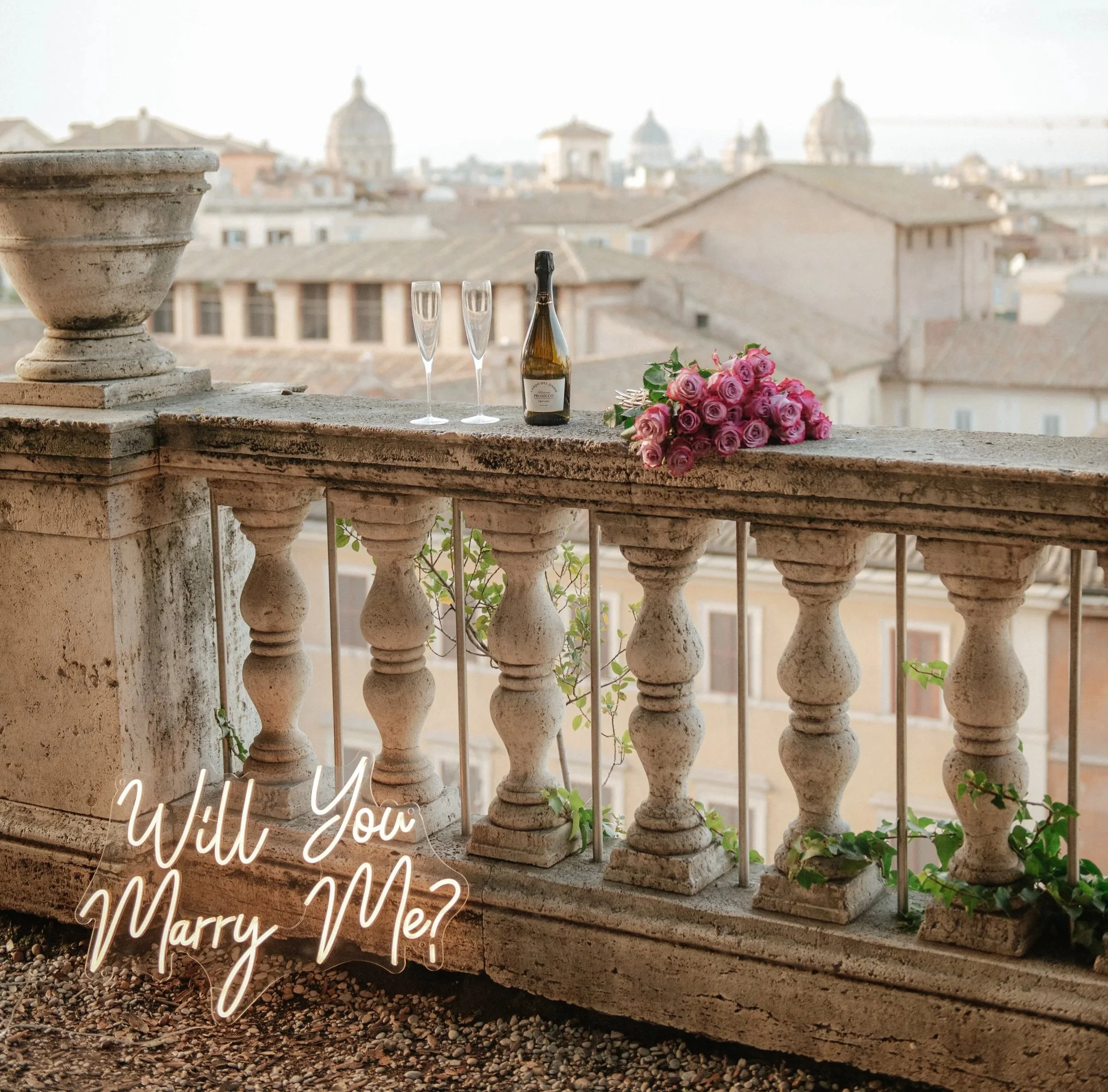 Romantic rooftop proposal setup in Rome with champagne glasses and flowers, overlooking the city, perfect idea for engagement celebration in Rome