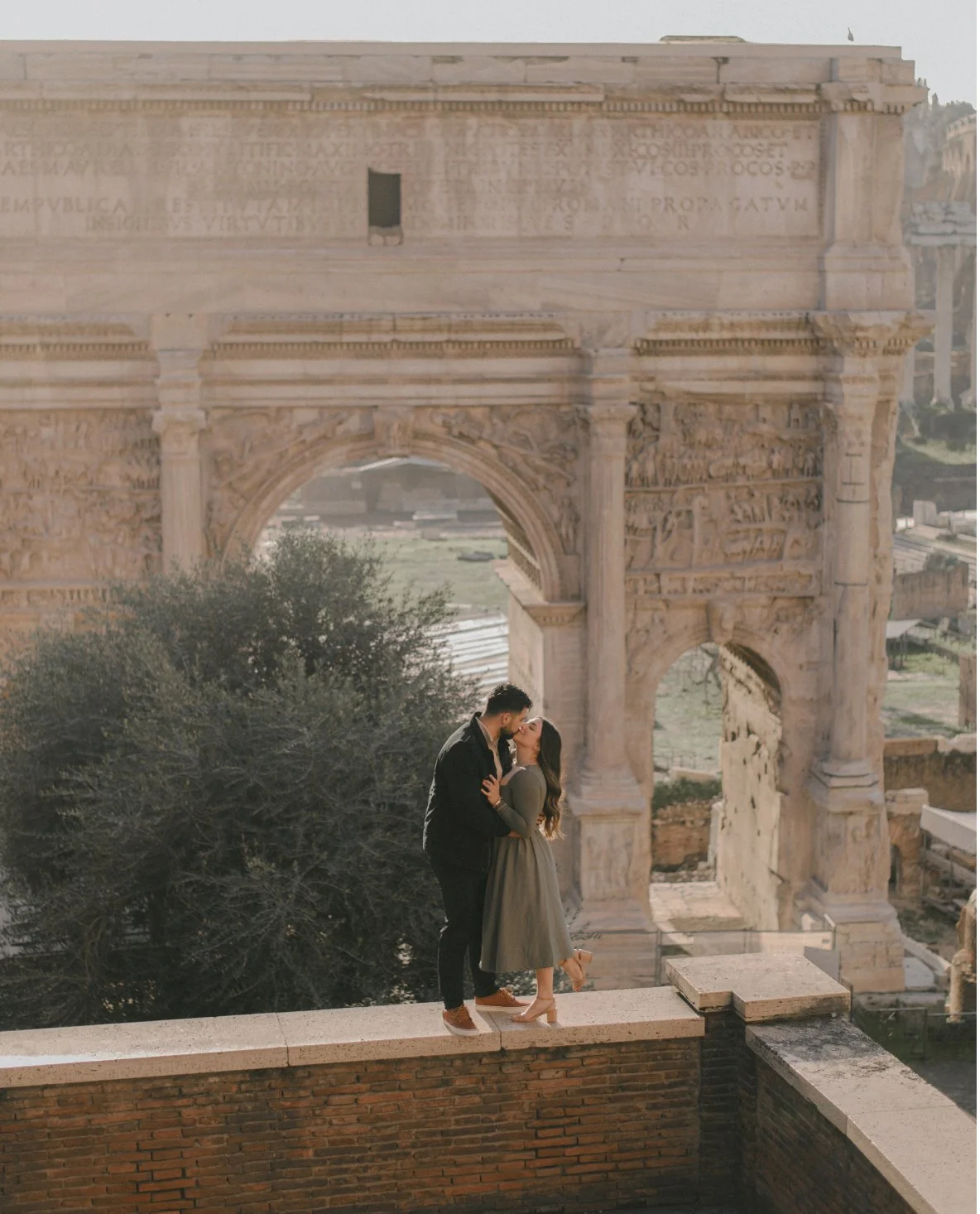 A couple kissing in front of the ancient Roman Arch of Constantine during sunset.