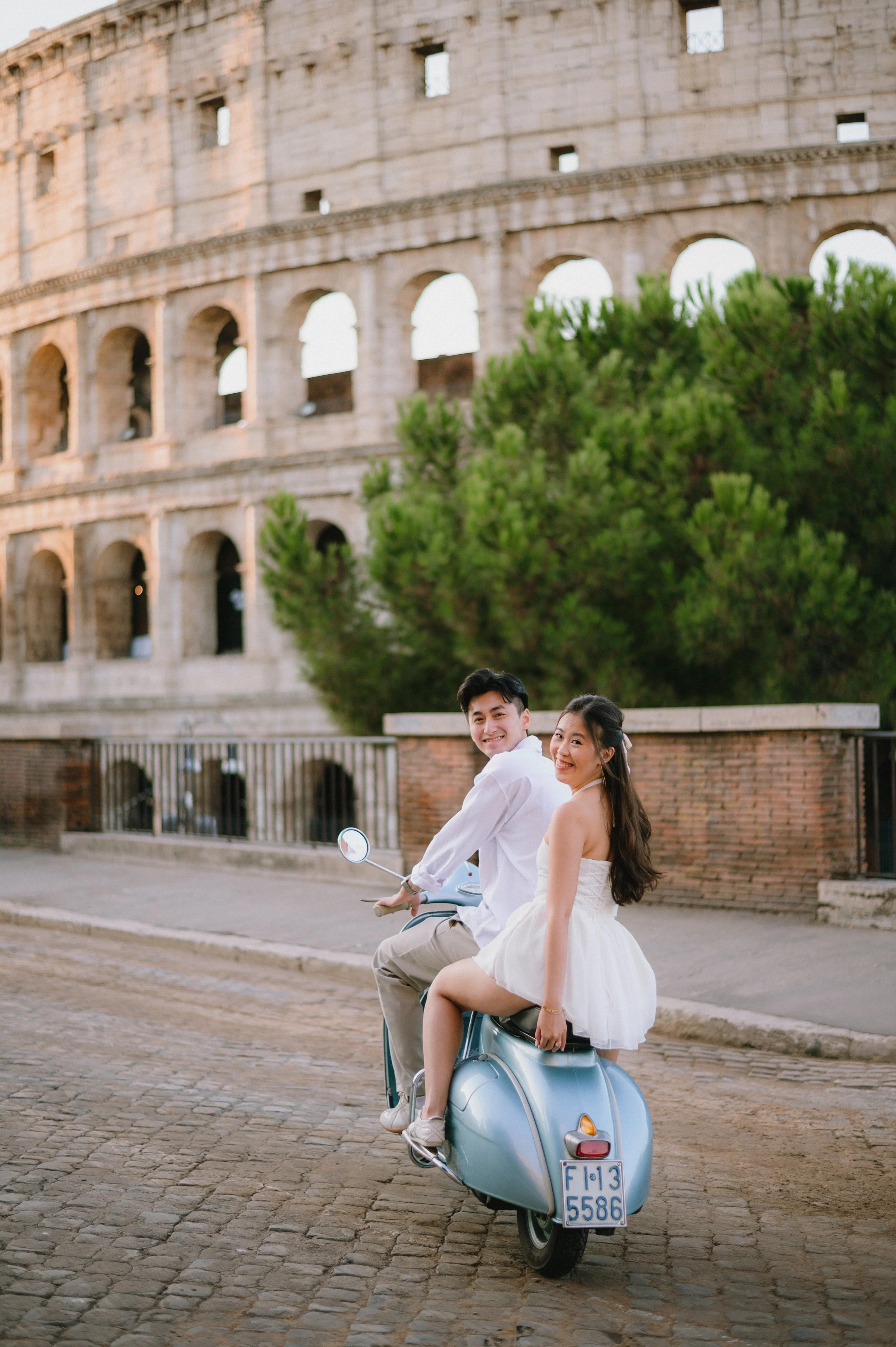 Romantic couple riding a vintage Vespa in Rome near the Colosseum, a unique and cinematic proposal idea in Rome