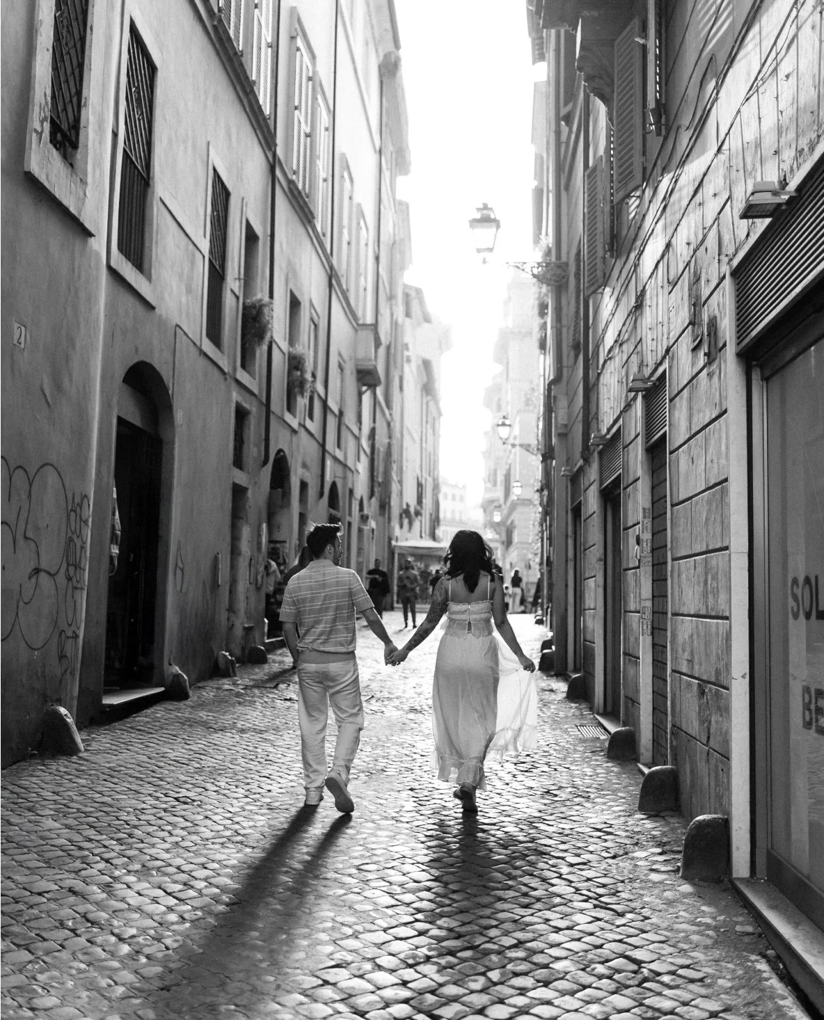 Black and white couple walking hand in hand in Rome street, cinematic photoshoot