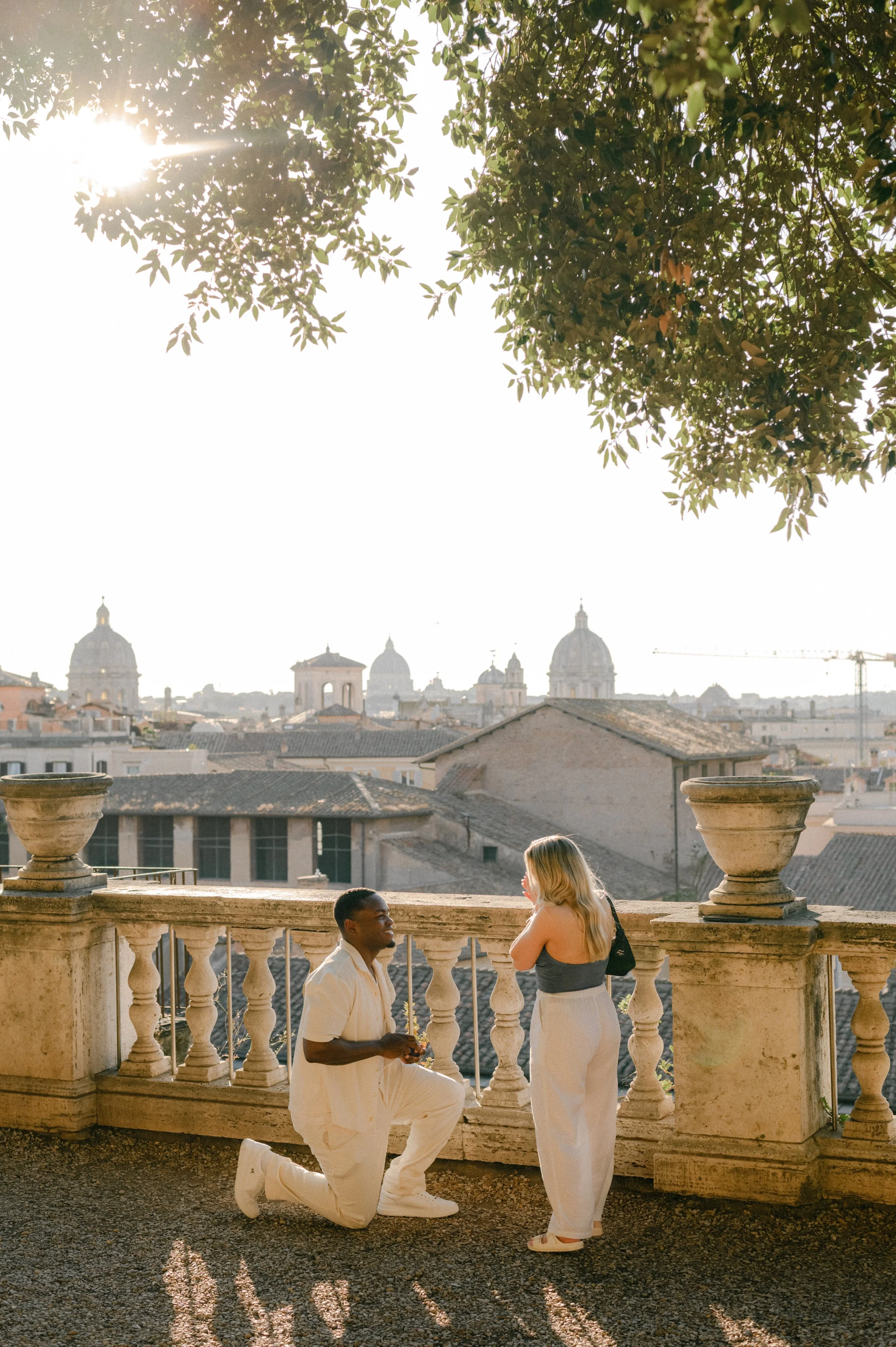 Surprise proposal in Rome with a man on one knee proposing at sunset overlooking the city