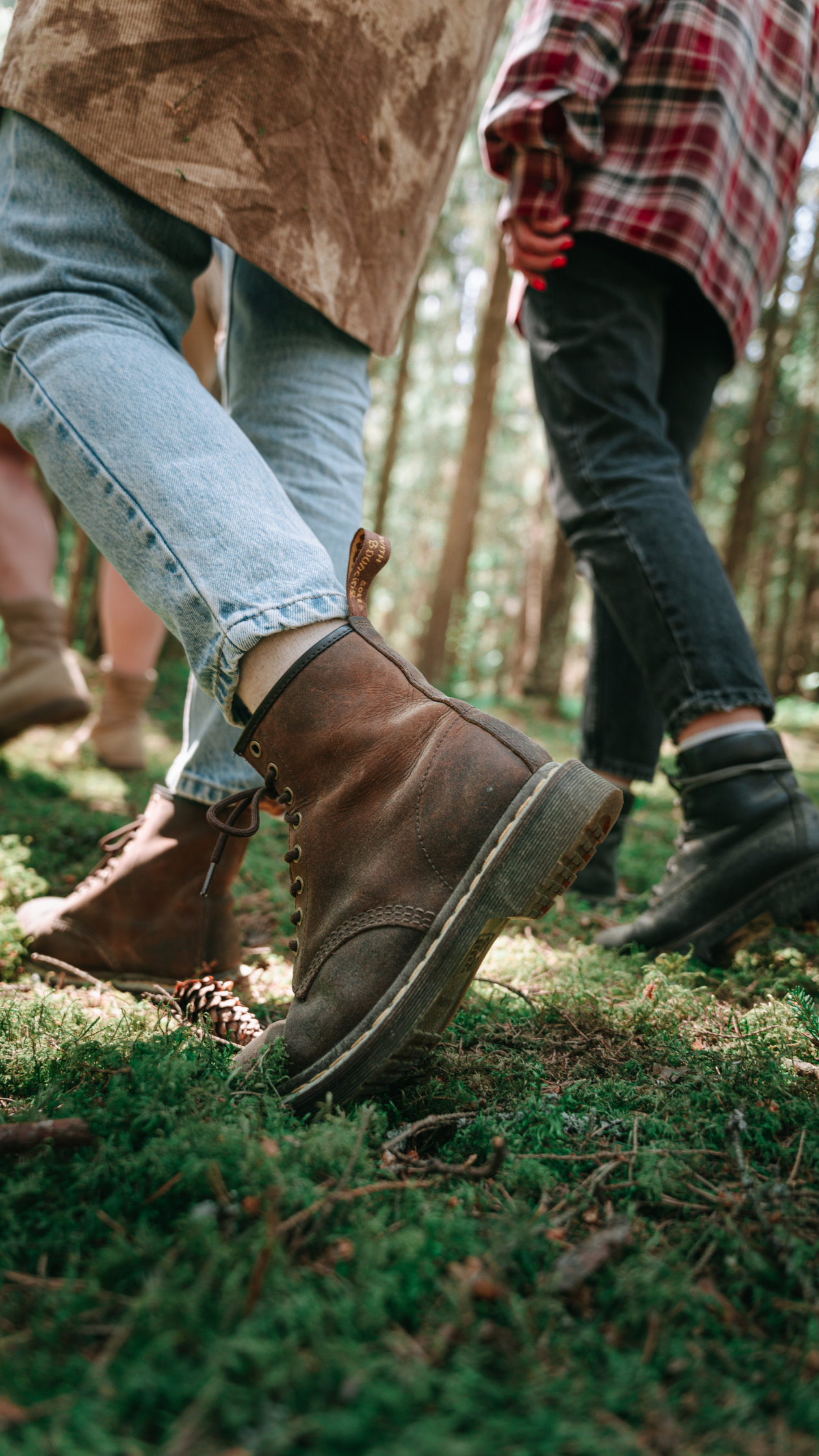 Side view of two people walking outdoors showing just legs and people wearing boots, jeans and shirts