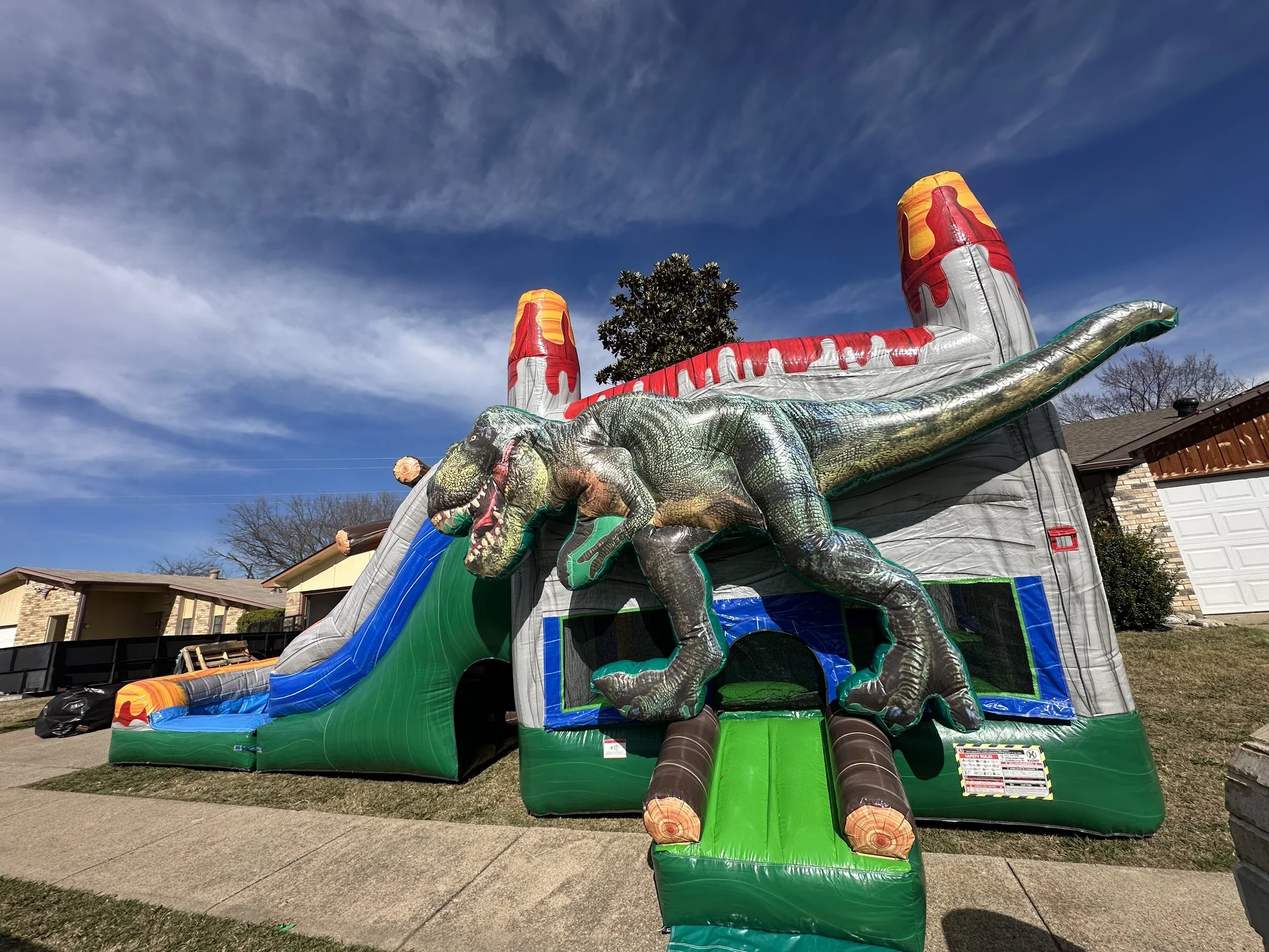 Inflatable jungle-themed bounce house with palm trees, dinosaurs, and a tiger face