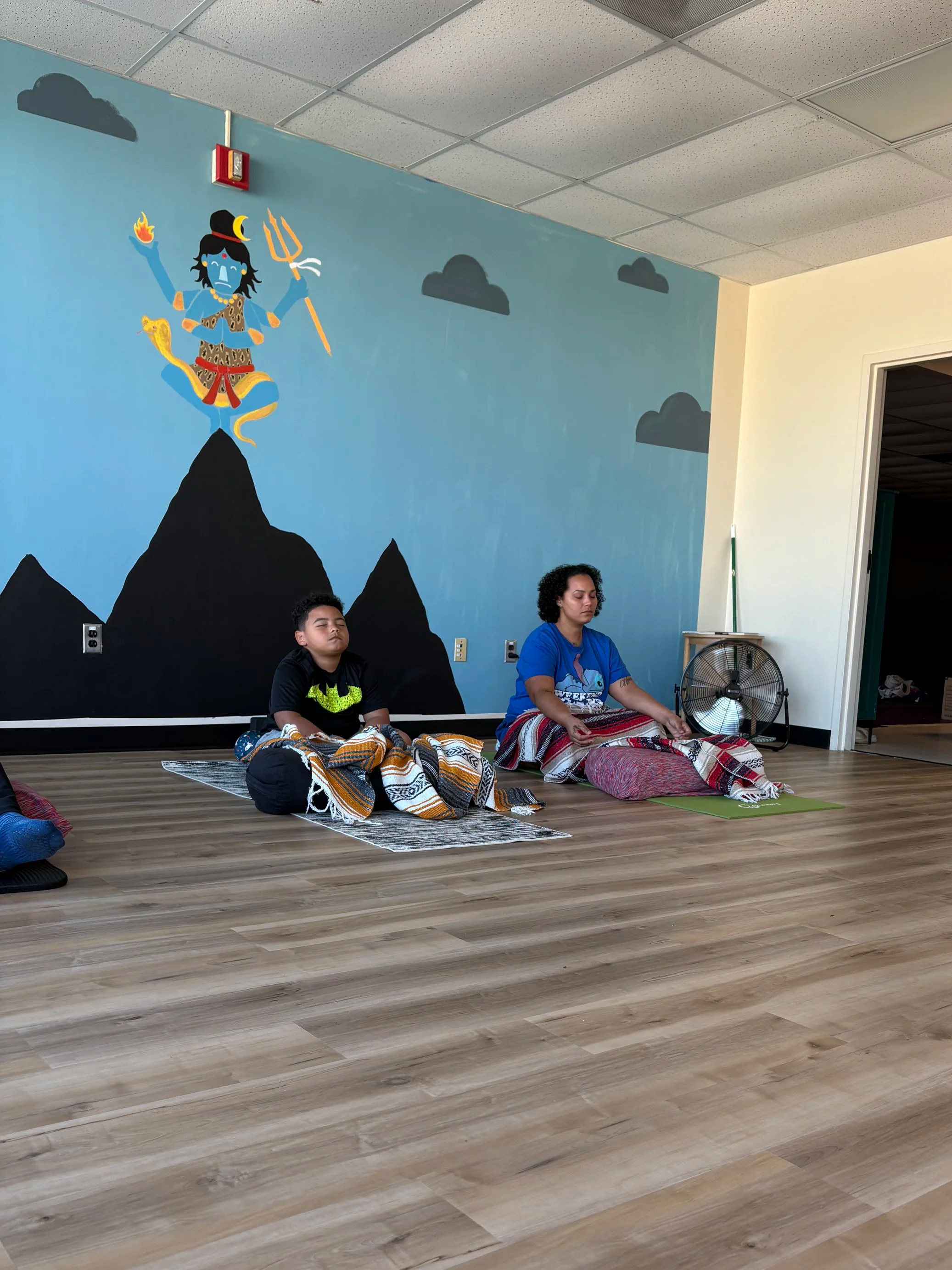 Mother and young son meditating in Sangha House Studio at Yoga Mouth Collective.