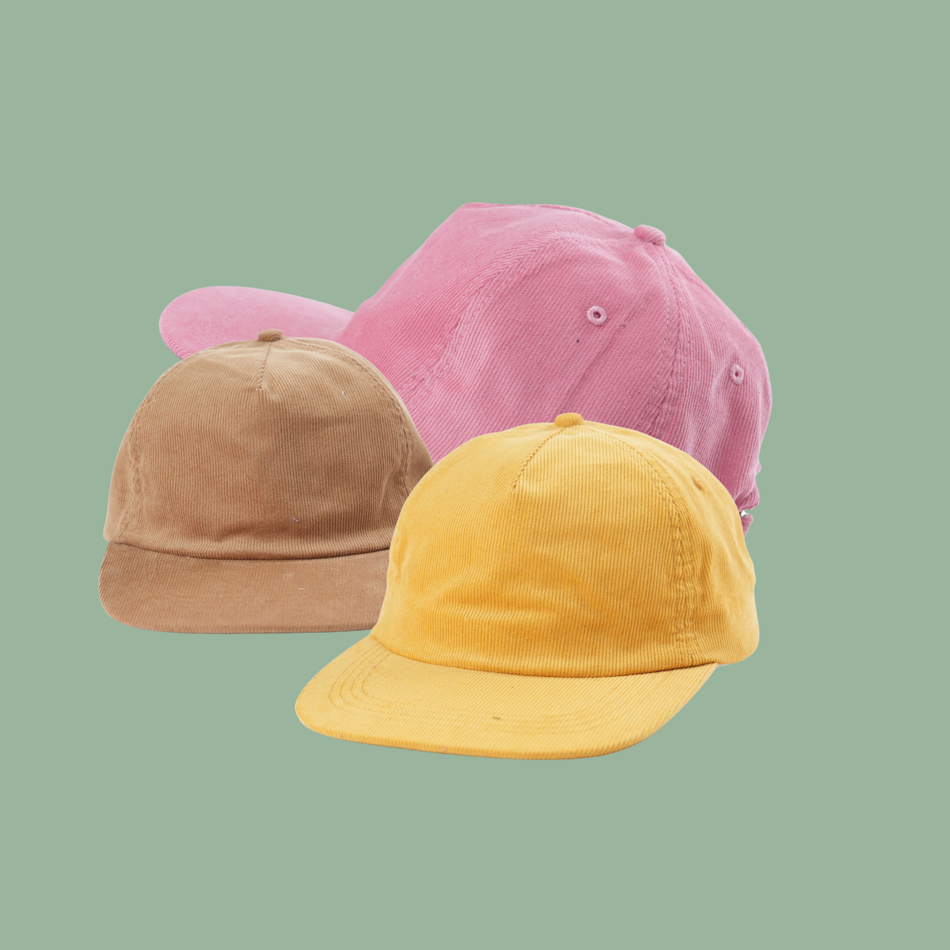 Drei bunte Cordkappen in Pastellfarben, rosa, gelb und beige, auf mintgrünem Hintergrund.