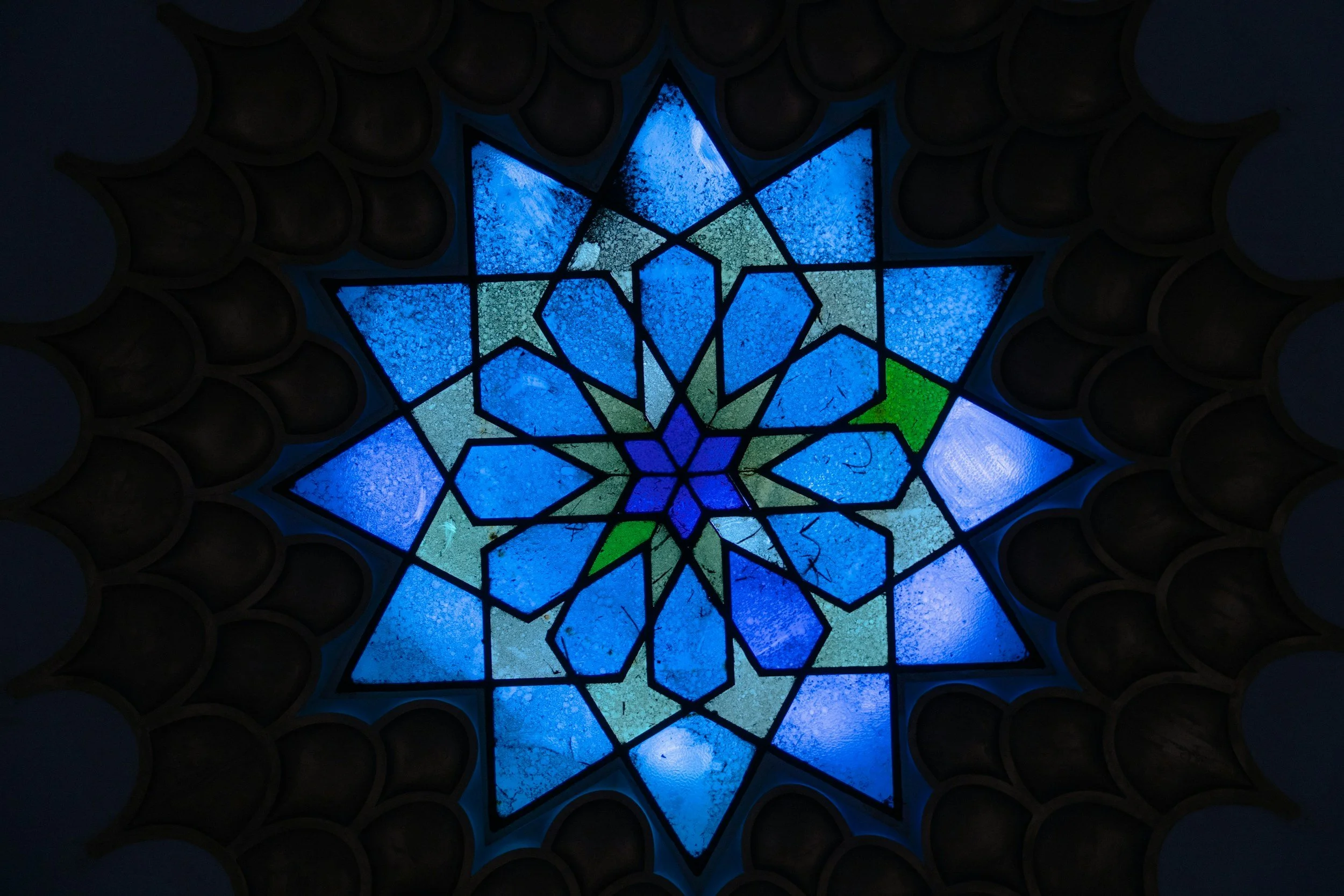 Colored stained glass ceiling with a star-shaped pattern in shades of blue with accents of green.