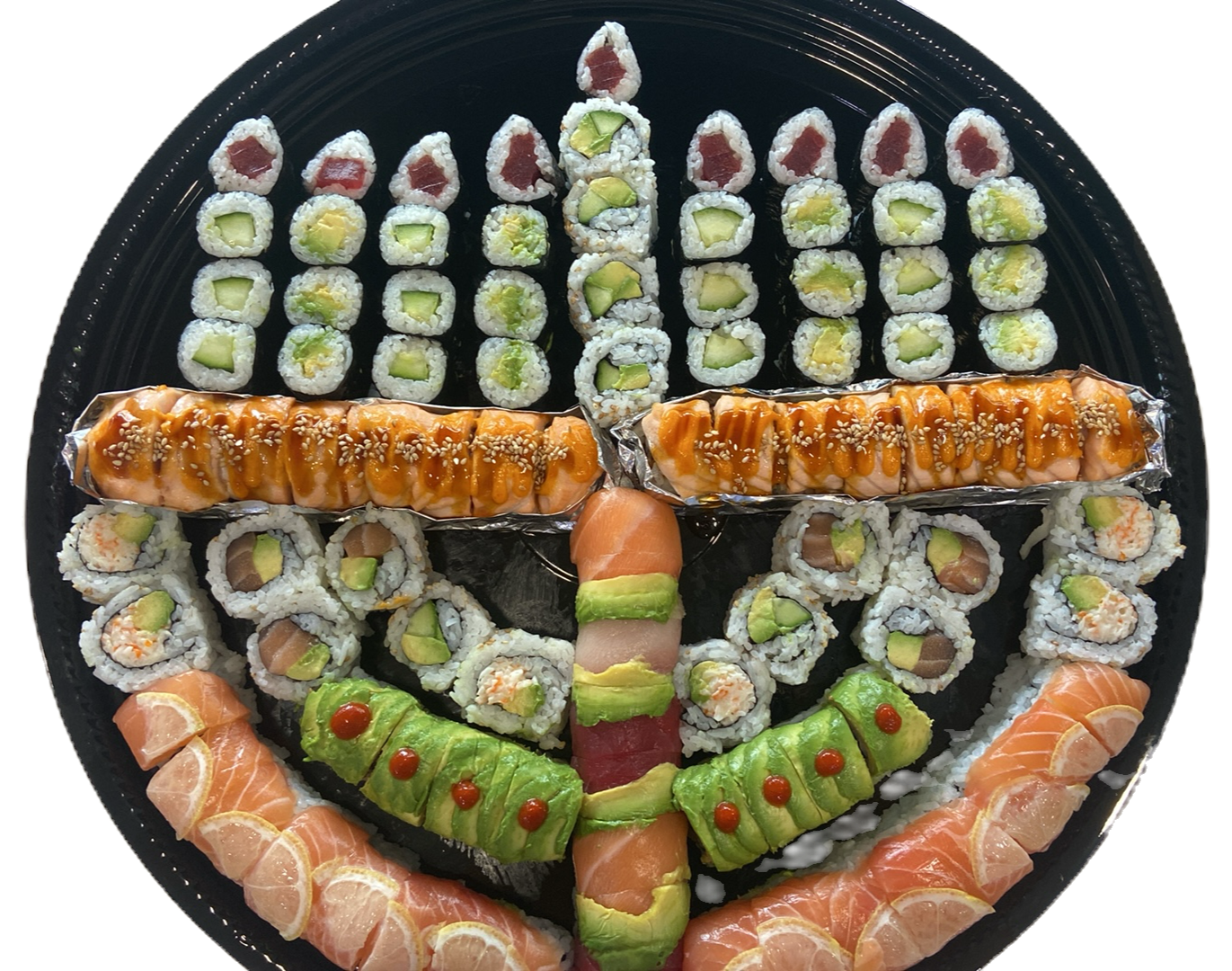 Assorted sushi rolls and sashimi on a round black platter, including salmon, avocado, and cucumber rolls, with some rolls topped with sauces and sesame seeds.