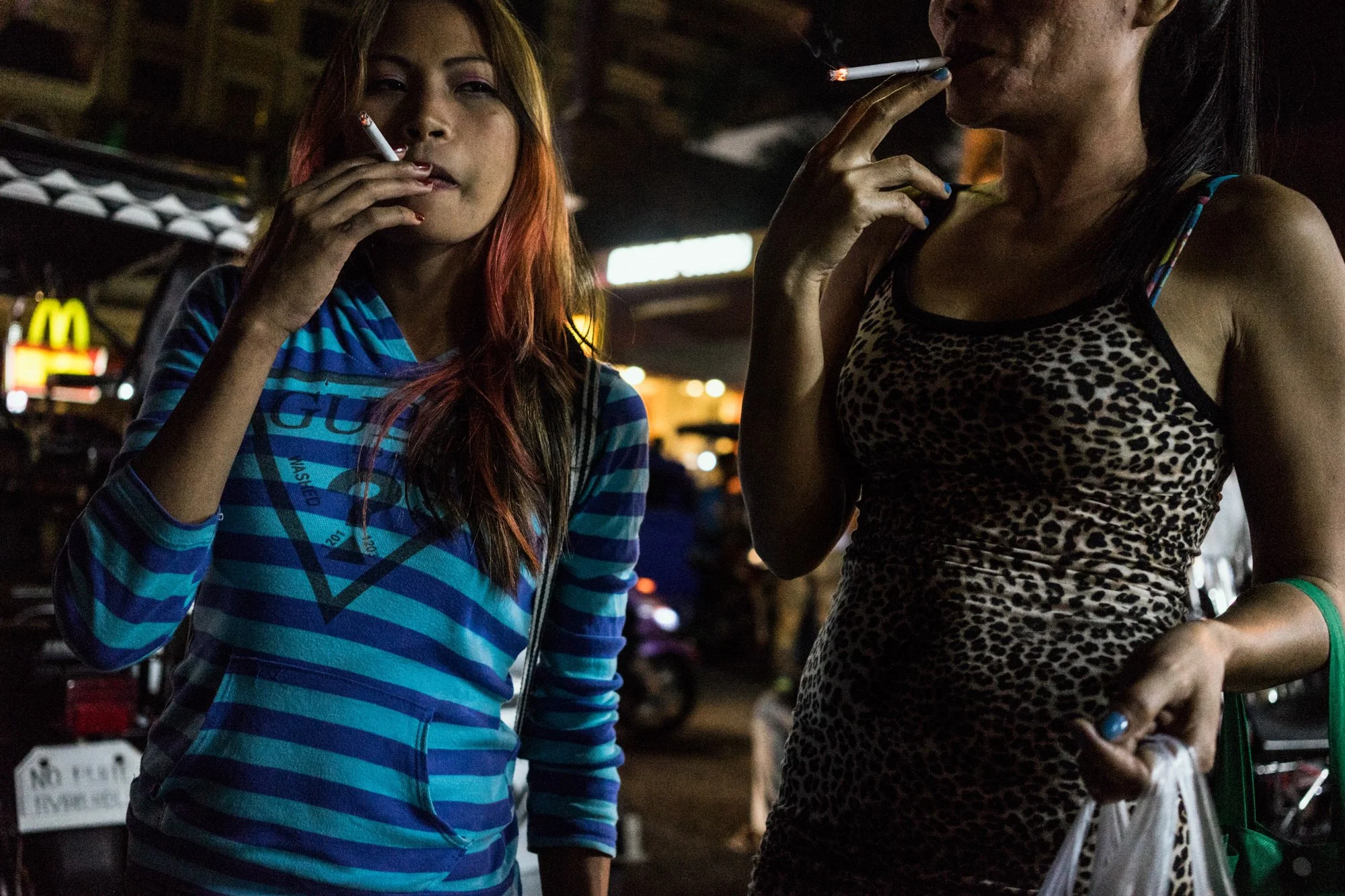 Jojo and Rose smoke cigarettes after a night at work in one of the bars in Angeles City. 