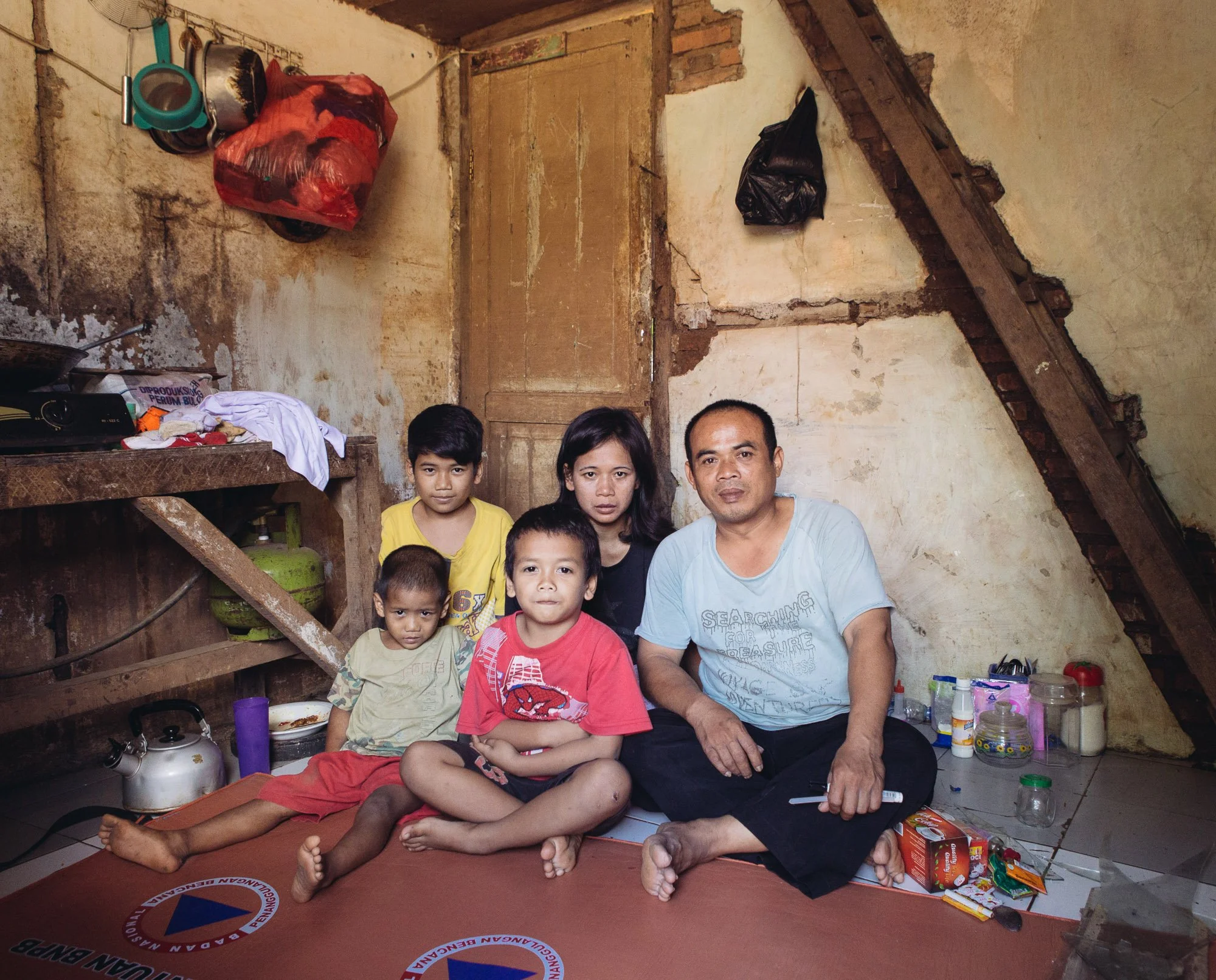 Residents living on the bank of the Ciliwung River pose for a photo in Kampung Melayu. Muhammad Syarifudin and Emi Wijayanti sit along with their three children. 