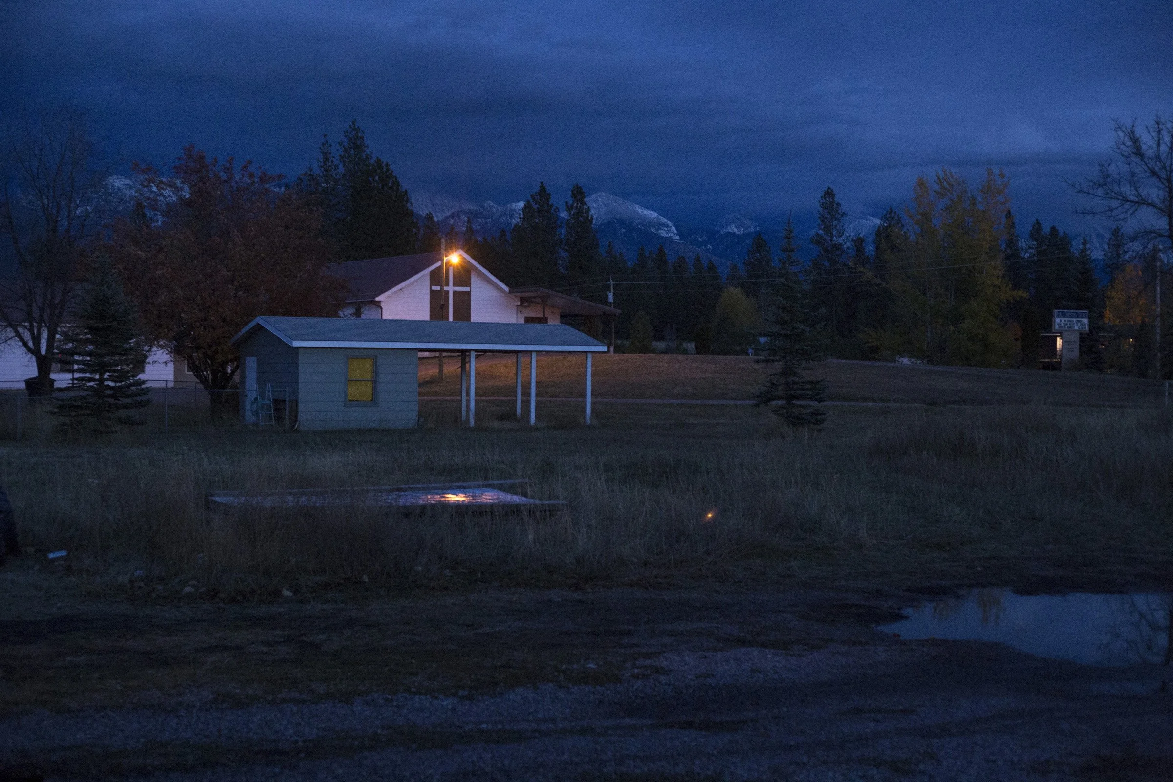  A church light shines as the sun falls behind the mountainside of Pablo, Montana, on Sunday, October 22, 2017. (Photo by Brittany Greeson) 