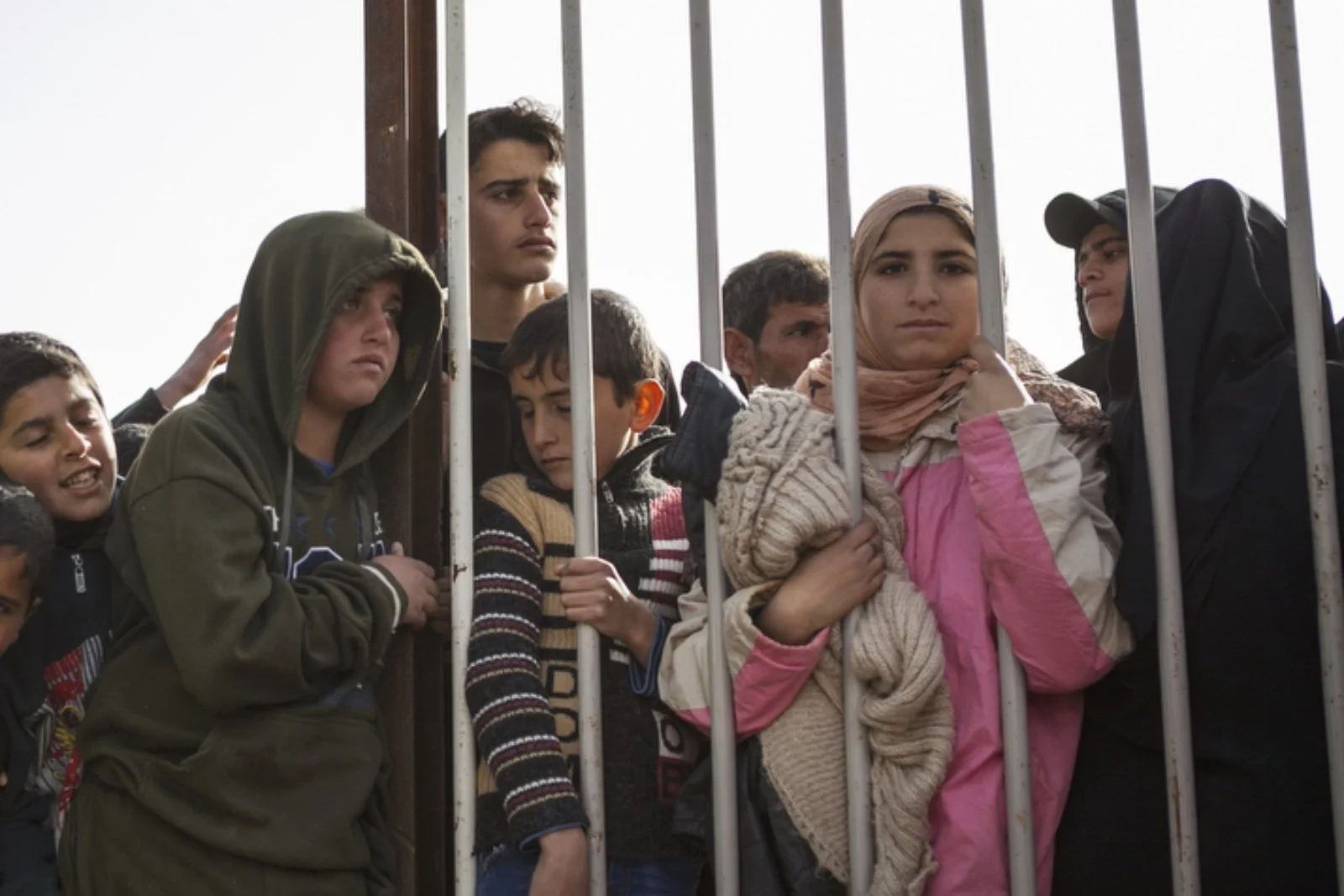 Children peer through the fence during distribution hours in Zaatari refugee camp on January 18, 2016. (Christopher Lee/GroundTruth) 