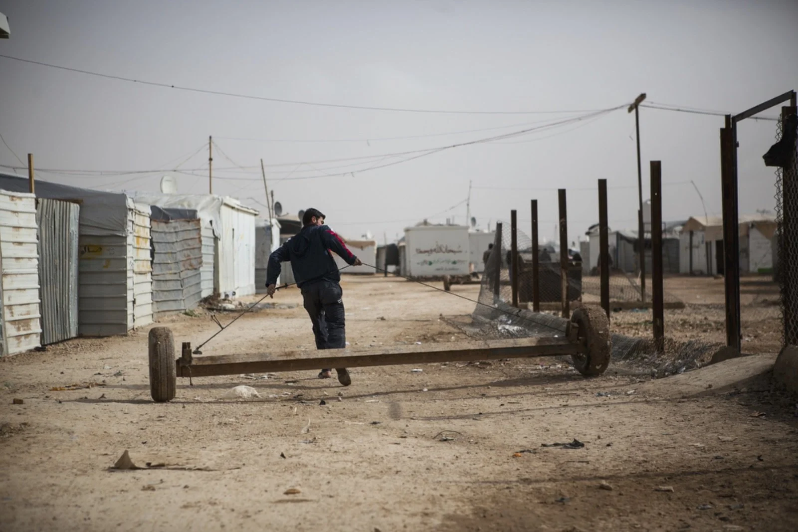  A Syrian refugee pulls a trailer that is used to haul large objects, including a whole caravan, down a street in Zaatari refugee camp on January 18, 2016. (Christopher Lee/GroundTruth) 