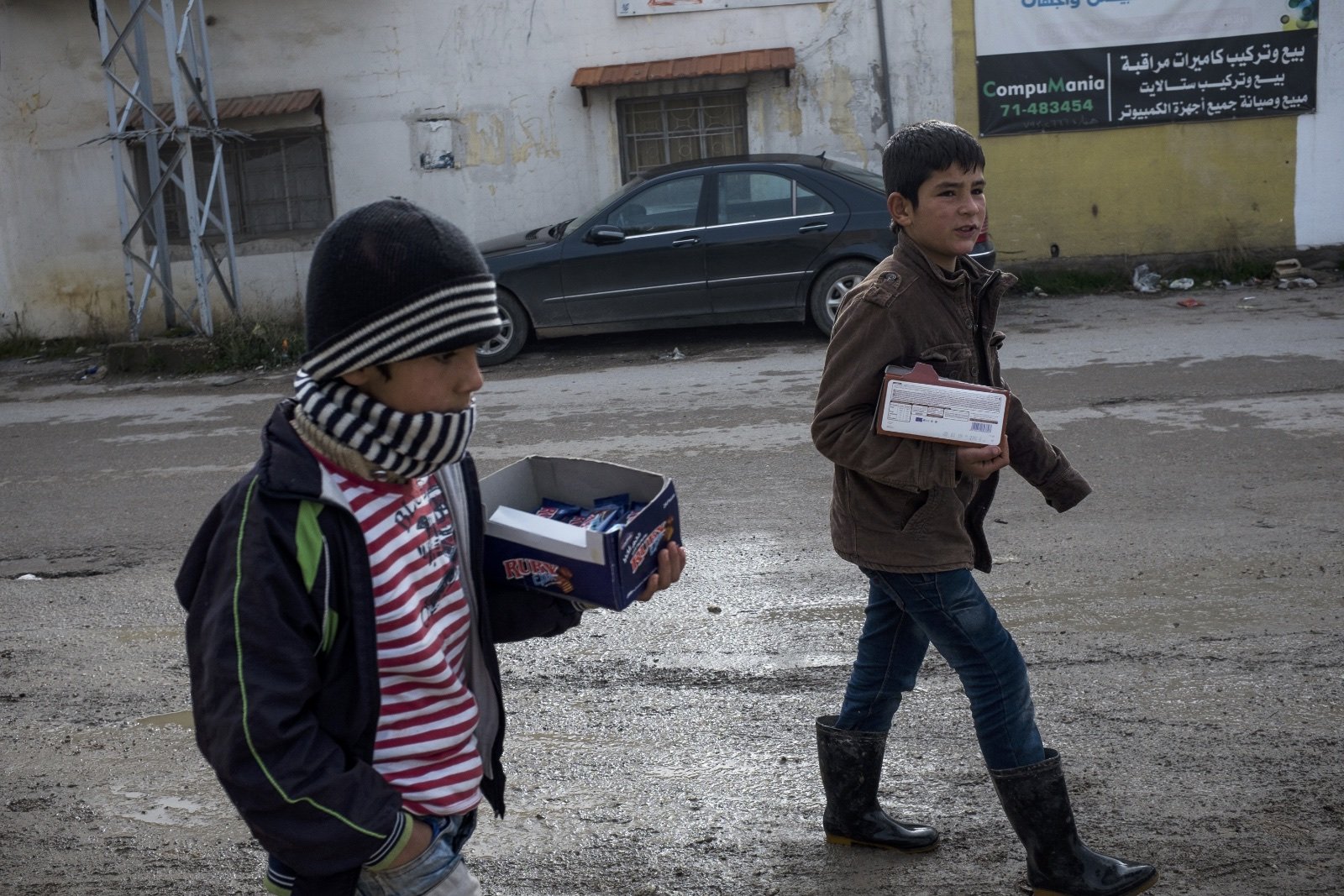  Mahmut (left), 8, a Syrian refugee from Homs, walks to the main street to sell biscuits with his brother, Khaled (right), 12, in the Bekaa Valley. (Christopher Lee/GroundTruth) 