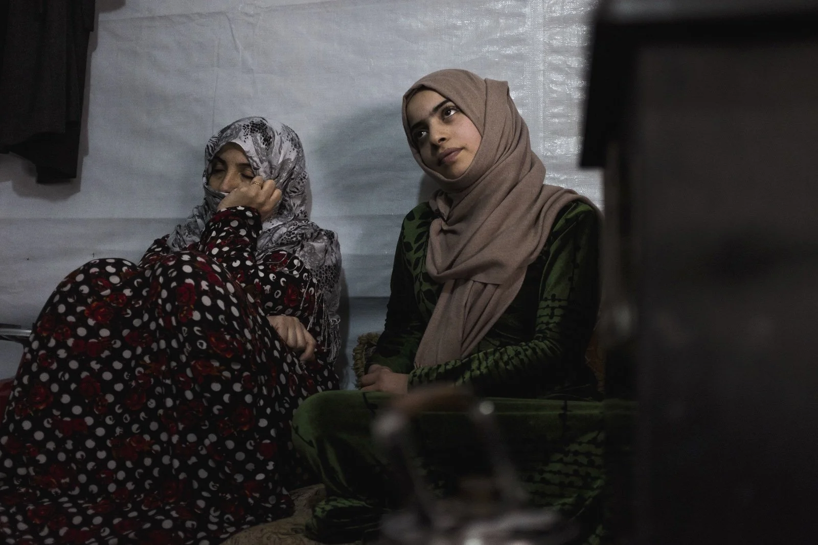  Batoul (right), 15, sits with her mother, Um Mohammad (left), in their improvised tent settlement. Batoul’s family got her married off when she was 13 out of fear for her safety. However, her husband has been physically and emotionally abusive and d