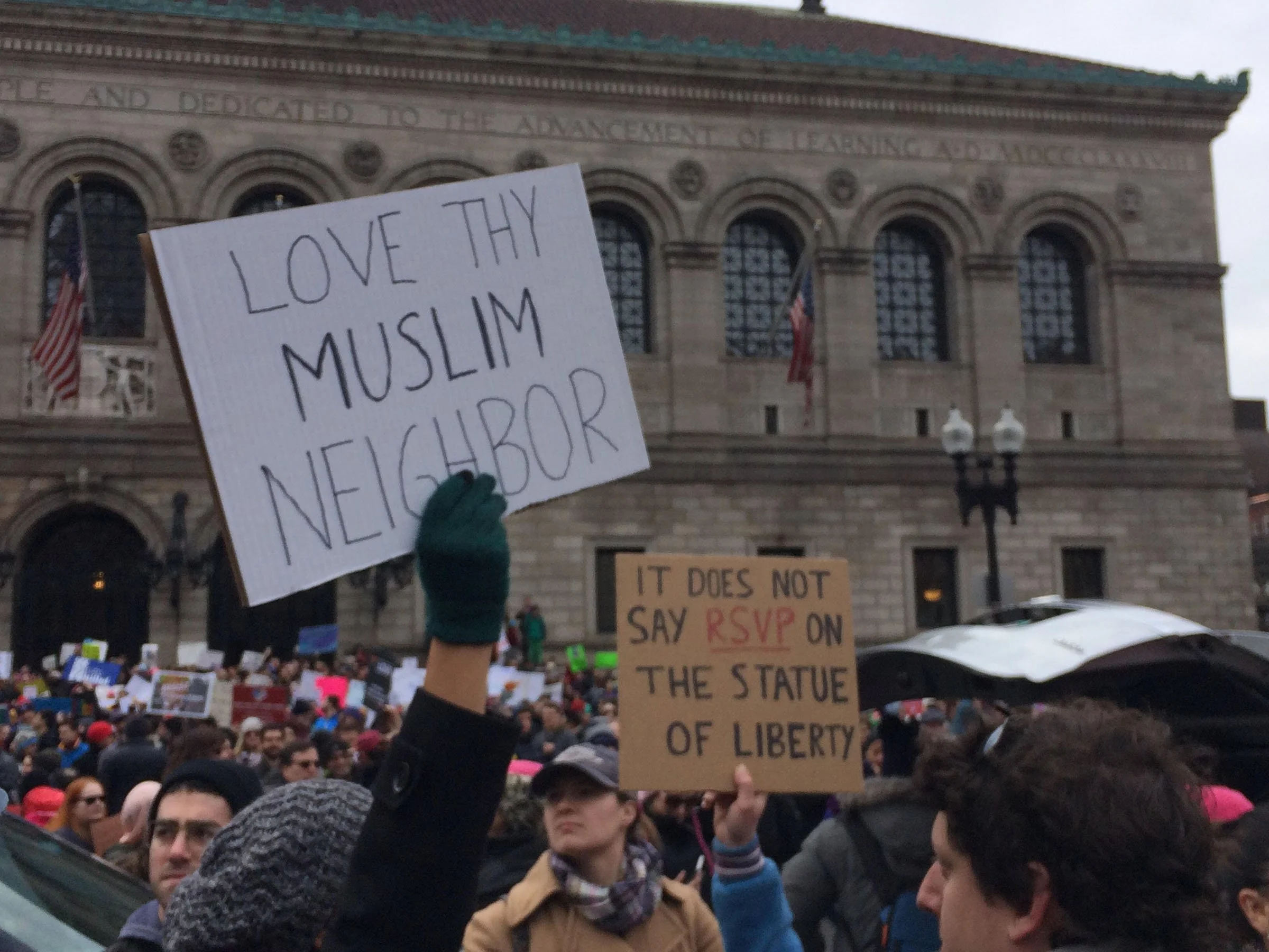  Signs read “Love thy Muslim neighbor” and “It does not say RSVP on the Statue of Liberty” at a demonstration in Boston’s Copley Square on January 29, 2017. (Photo by Giulia Afiune/GroundTruth) 