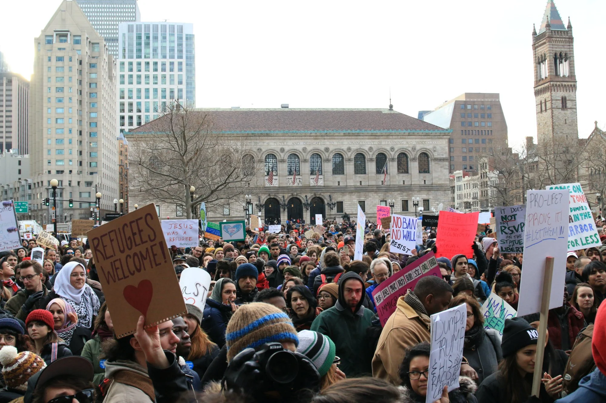  A crowd gathers in protest against President Donald Trump’s immigration ban, in front of the Boston Public Library on Jan. 29, 2017. Signs read “Refugees welcome” and “Jesus was a refugee.” (Photo by Giulia Afiune/GroundTruth) 