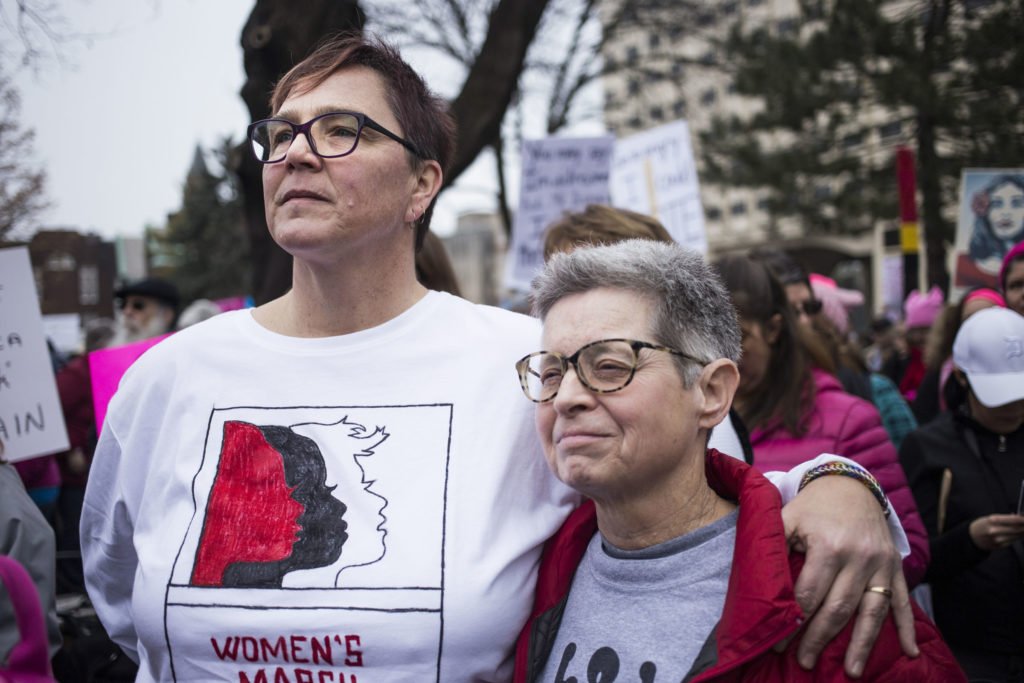   Lisa Mapp, 54, and marital partner, Chris Smith, 44, of Mason, Mich., embrace while listening to speakers during the Women’s March on Lansing outside of the Michigan State Capitol Building in Lansing, Mich., on Saturday, January 21, 2017. The pair 