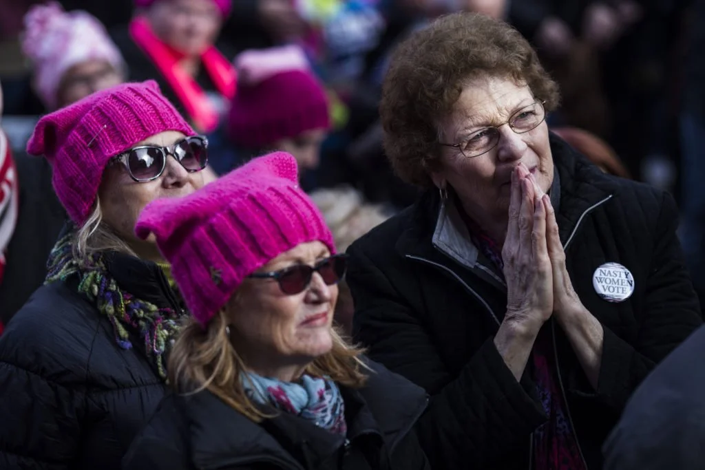   Mille Wrench, 72, of Kalamazoo, Mich., listens to speakers during the Women’s March on Lansing outside of the Michigan State Capitol Building in Lansing, Mich., on Saturday, January 21, 2017. (Photo by Brittany Greeson/GroundTruth)  