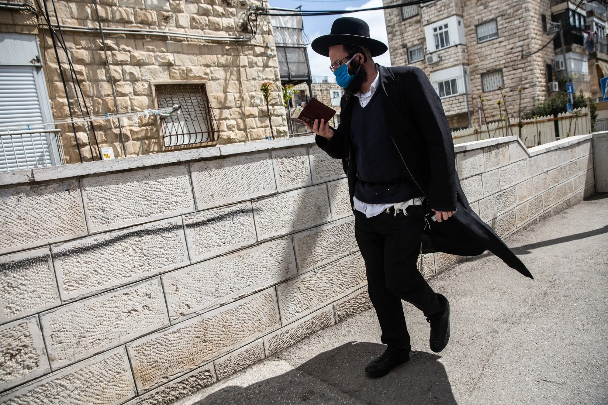  An ultra-Orthodox Jew wears a protective mask while reading a prayer book in the Jerusalem neighborhood of Mea Shearem on April 4, 2020. (Photo by Heidi Levine/GroundTruth) 