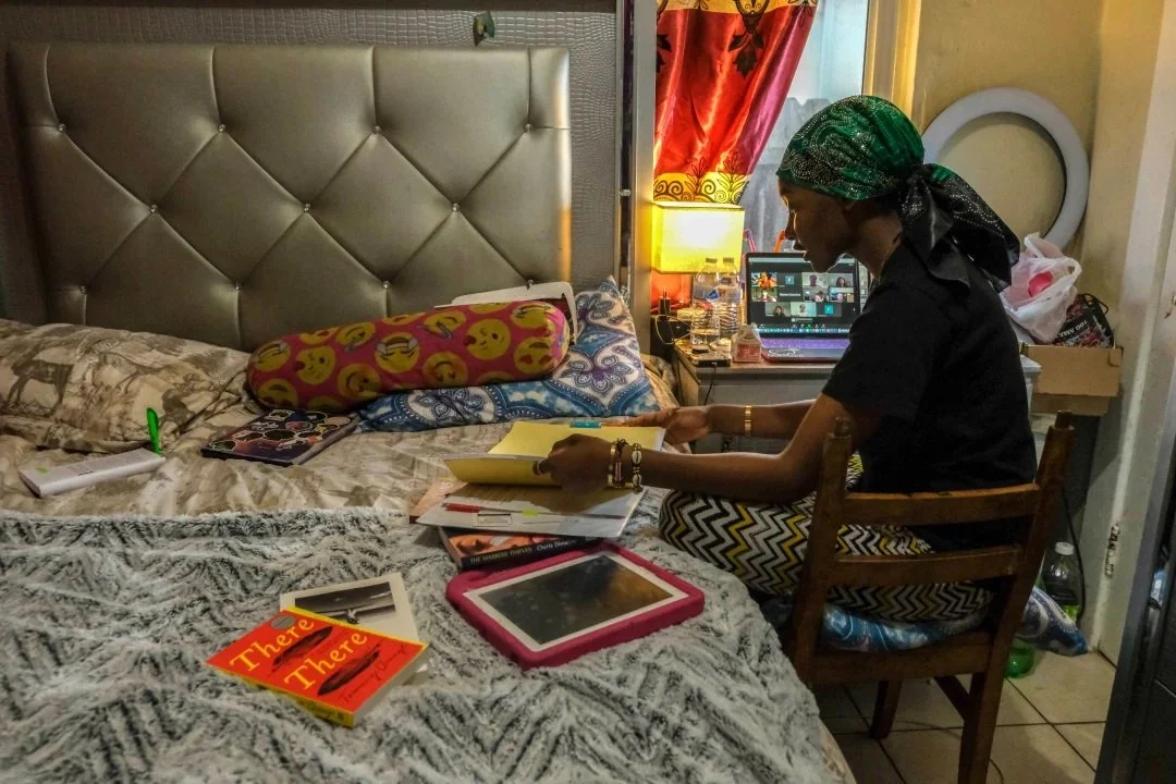  In the bedroom that she shares with her children, Musa sorts through notebooks and class materials for her UCSD indigenous literature course. With two elementary school children of her own, Musa also navigates online learning at UCSD. (Photo by Arya