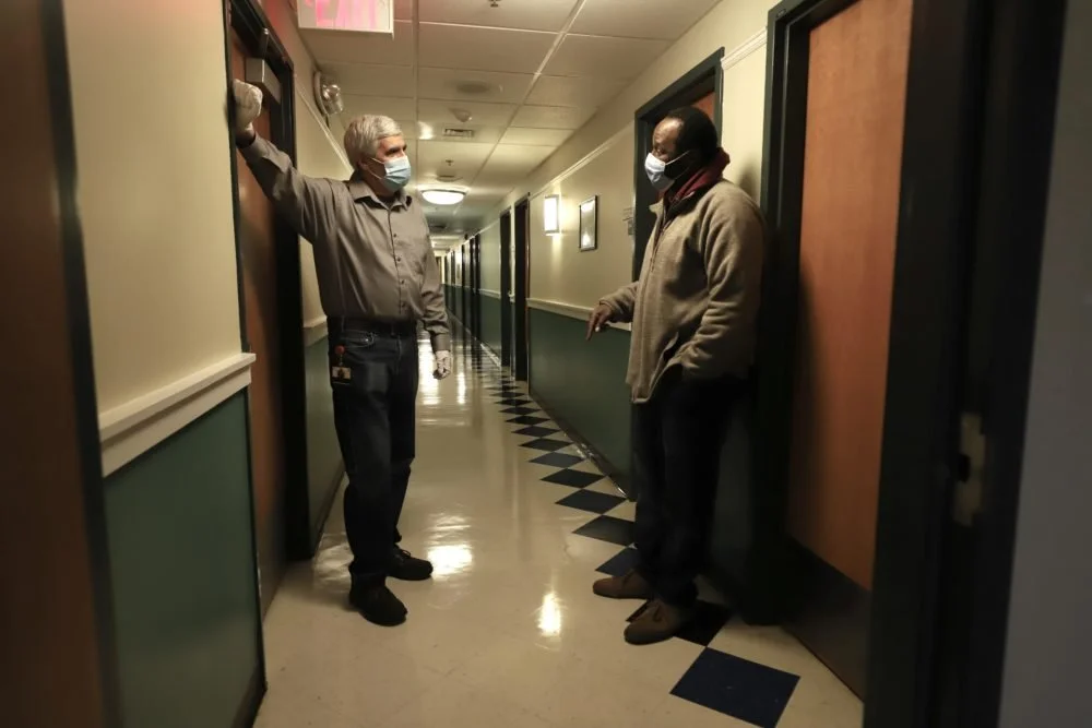  Columbus House Chief Development Officer John Brooks speaks to a shelter staff worker on the medical respite program floor in New Haven. (Photo by Chris Ehrmann/GroundTruth) 
