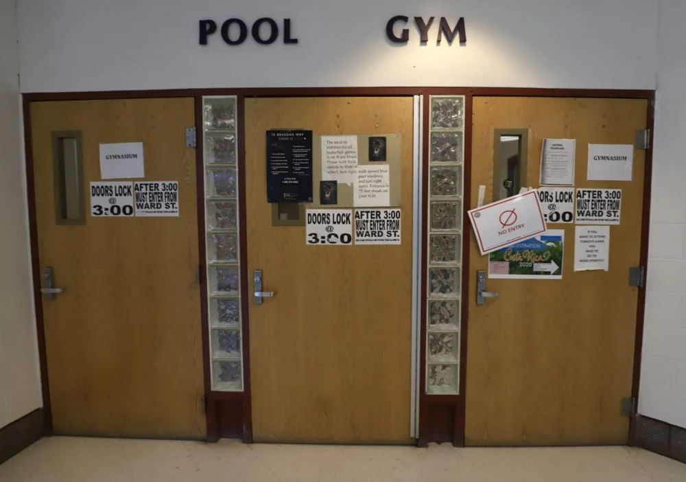  The door to the gymnasium before the makeshift wooden barrier that separates patients sick with COVID-19 at Hill Regional Career High School in New Haven. (Photo by Chris Ehrmann/GroundTruth) 