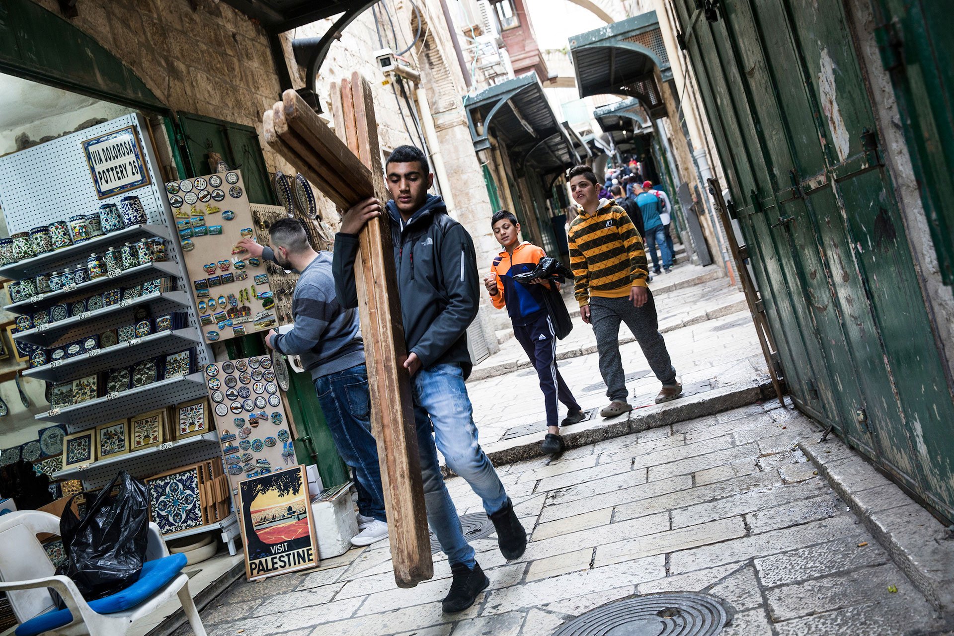 A Palestinian walks carries wooden crosses along the Via Dolorosa for the Christian worshipers during the Good Friday procession in Jerusalem’s Old City on March 30,2018.(Photo by Heidi Levine for The GroundTruth Project)