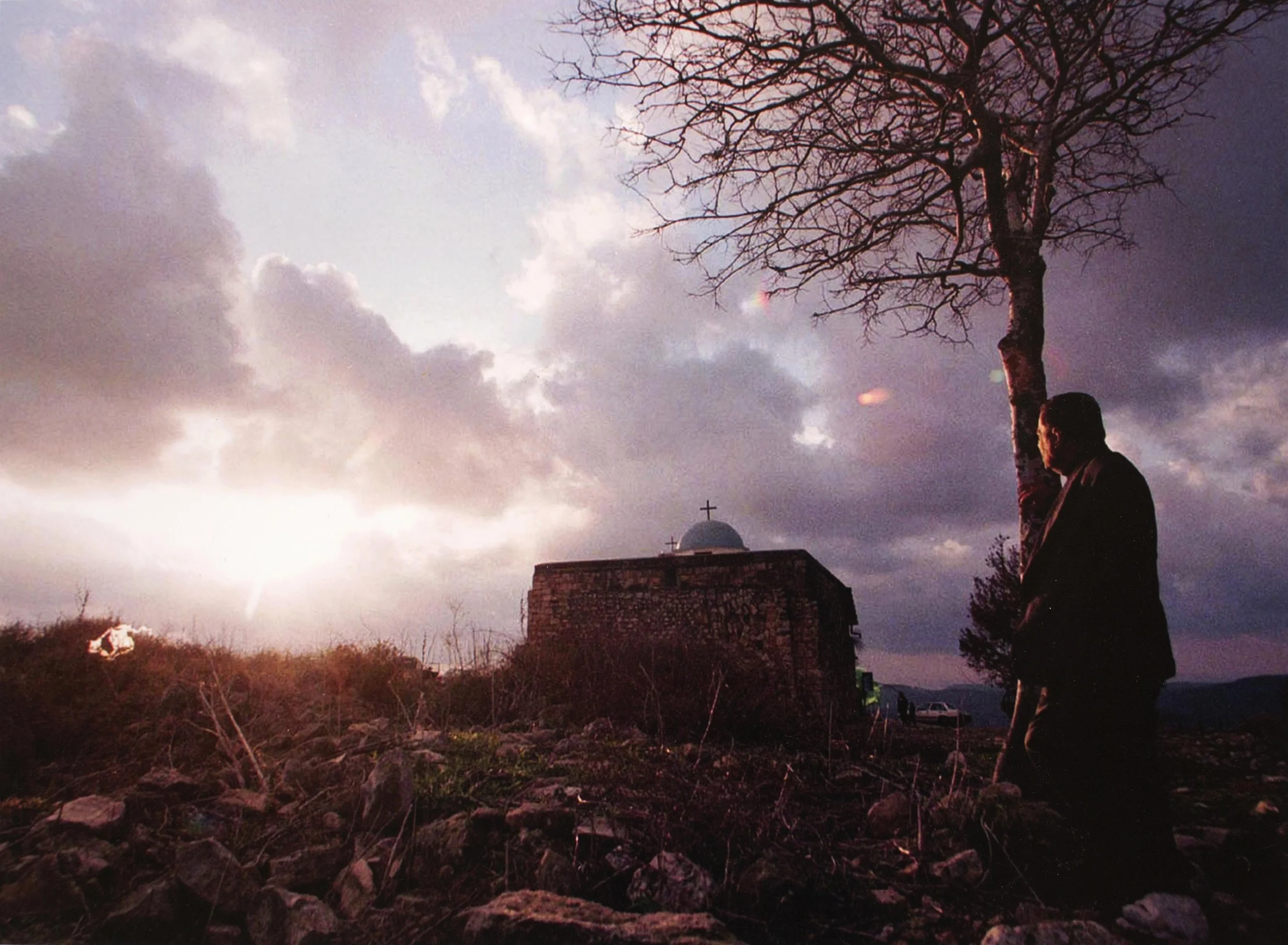 Elias Khoury, a Christian Arab, gazes at the church in Iqrit in December 1998. Khoury was born in Iqrit, where residents were forced out a half-century ago. On Christmas, they still attend services at the old stone church. (Photo by Heidi Levine)