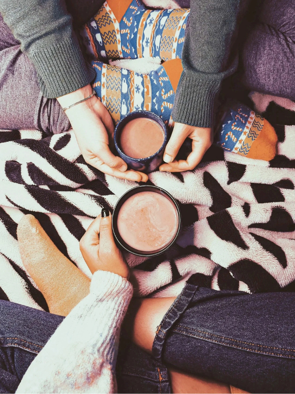 Two cups of coffee on a cozy blanket while two people spend time together representing caregiver therapy