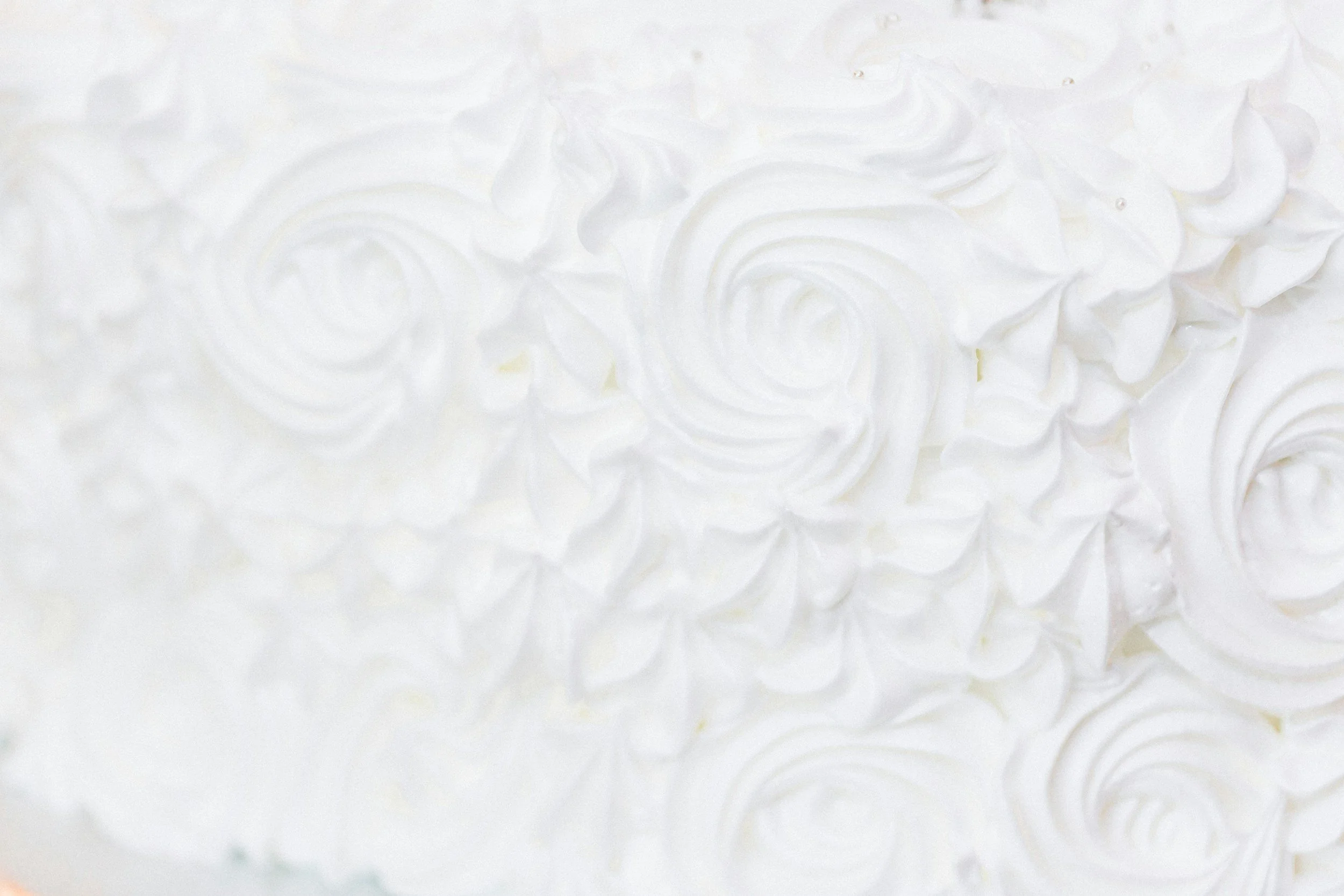 Close-up of white frosting with scalloped patterns on a cake