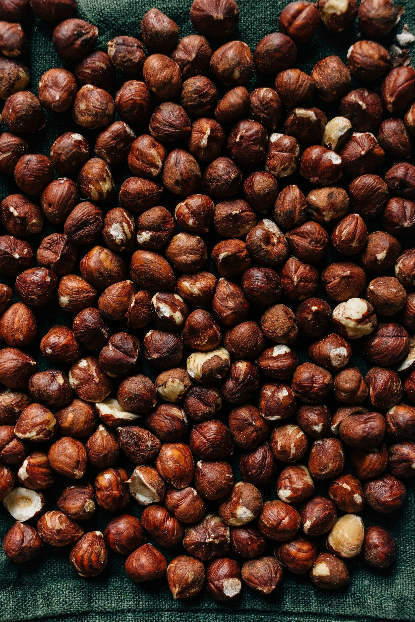 Heap of whole hazelnuts on dark fabric background