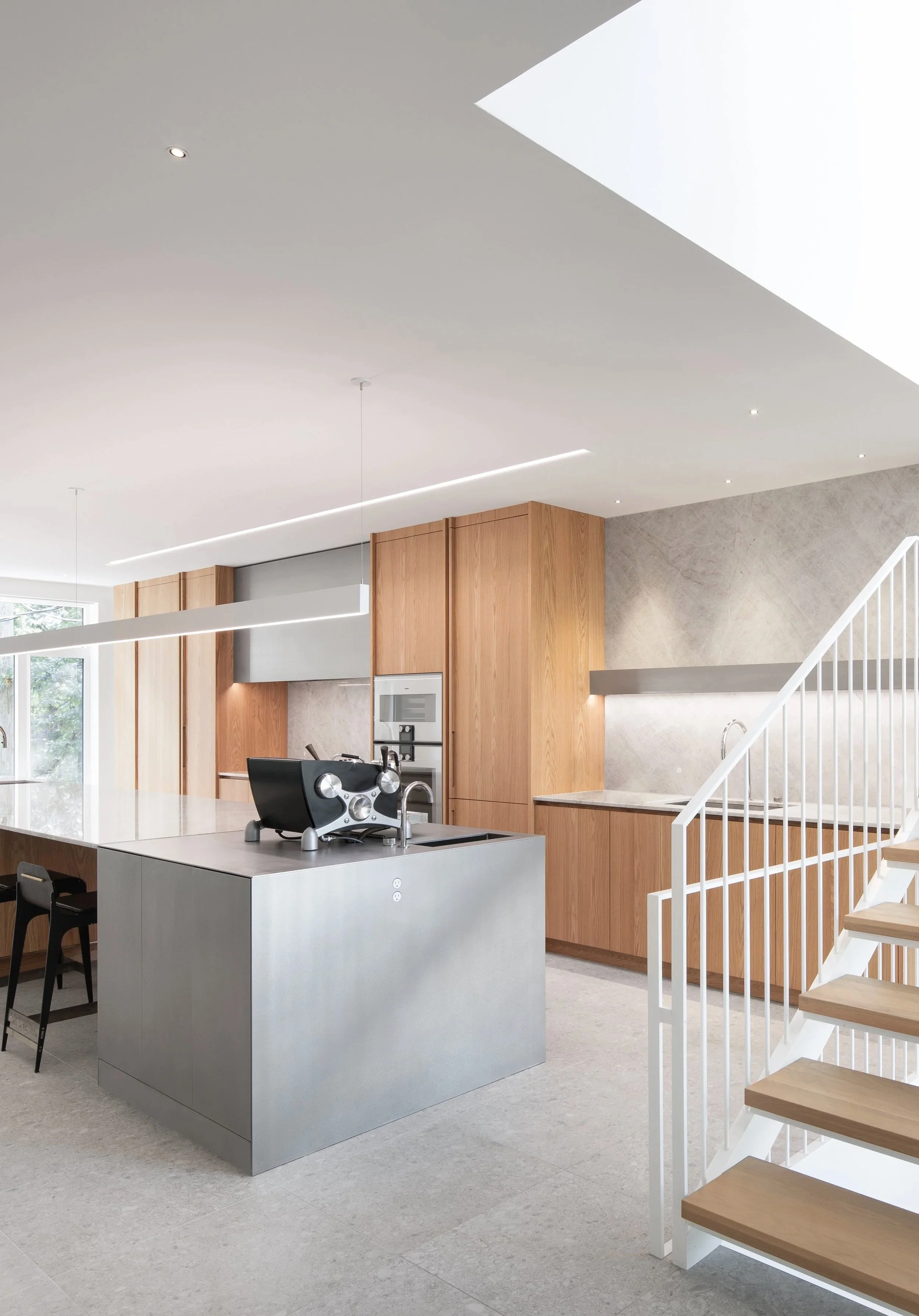 Cuisine contemporaine baignée de lumière naturelle avec îlot central et matériaux texturés
