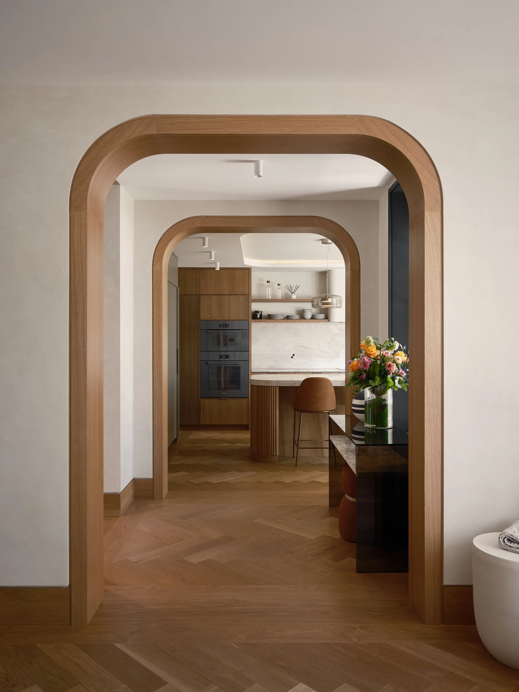 Arches en bois réalisées sur mesure créant une continuité entre la cuisine et les espaces adjacents.