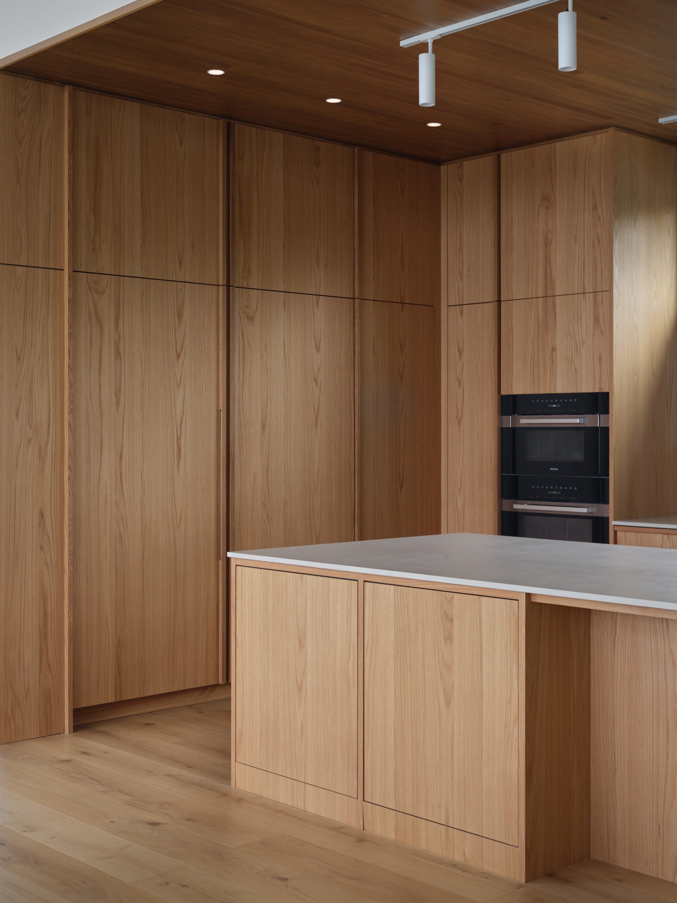 Armoires de cuisine en bois sur mesure intégrées dans une composition minimaliste et intemporelle.