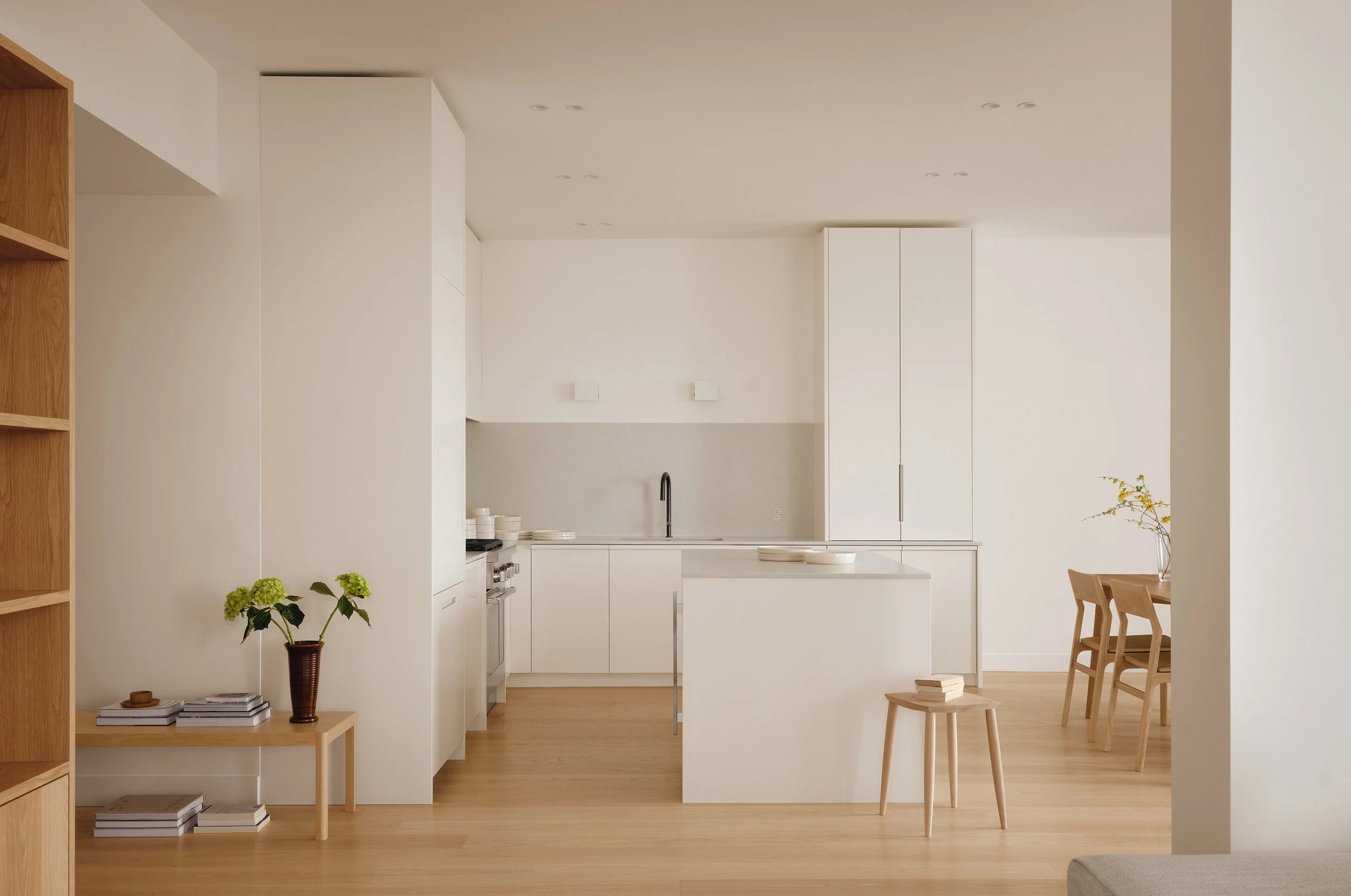 Cuisine minimaliste entièrement blanche avec comptoir gris pâle.