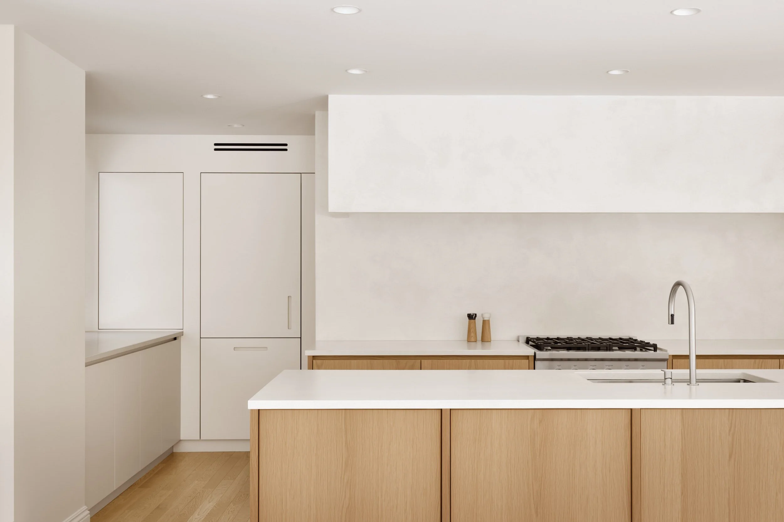 Cuisine haut de gamme sur mesure avec îlot en bois clair et volumes épurés mettant en valeur les proportions de l’espace.