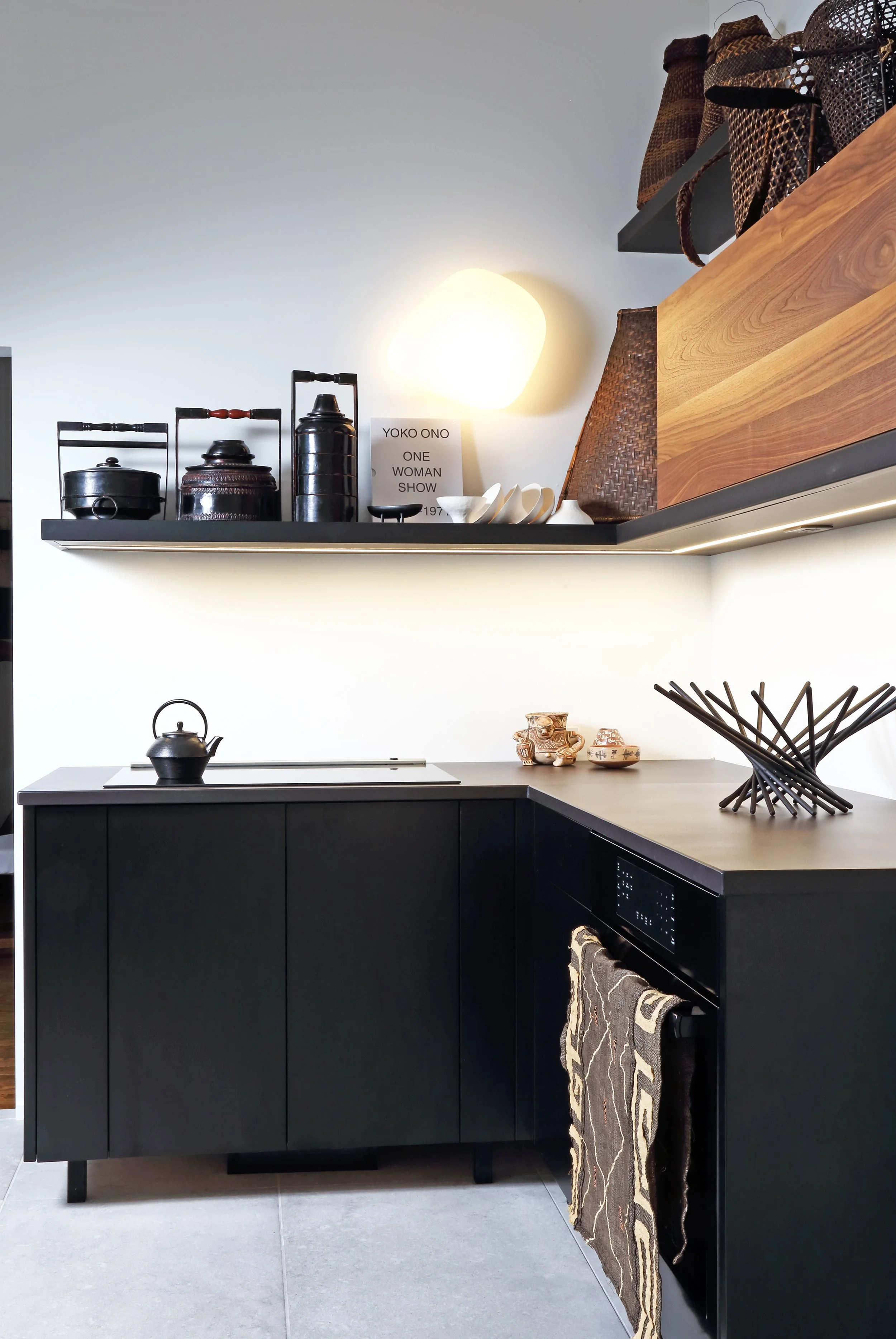 Kitchen in black lacquer and American walnut. Decorative objects, wicker baskets, sculptures, books, paintings in a maximalist setting.