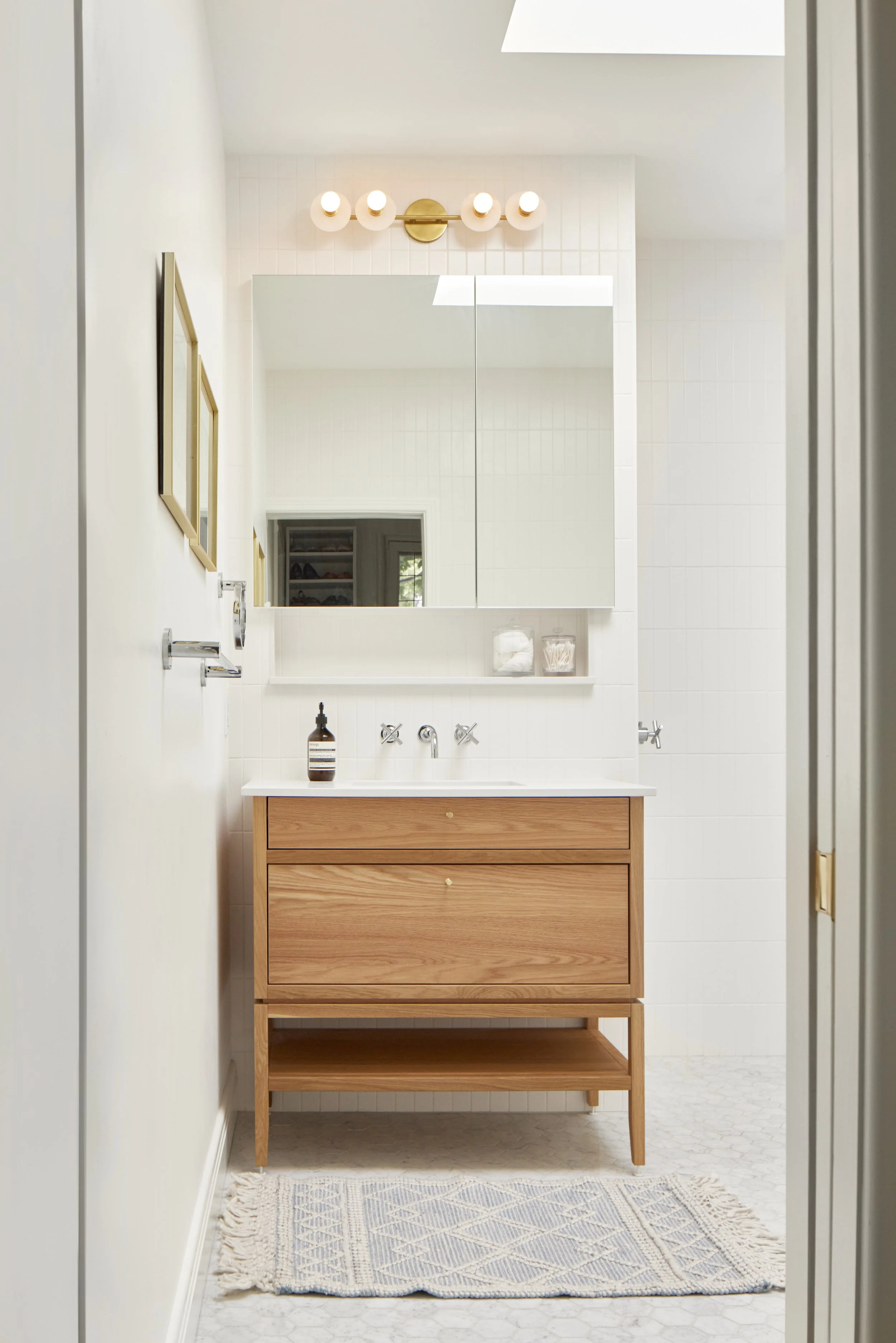 Vanité salle de bain, bois clair, comptoir blanc, robinet mural.