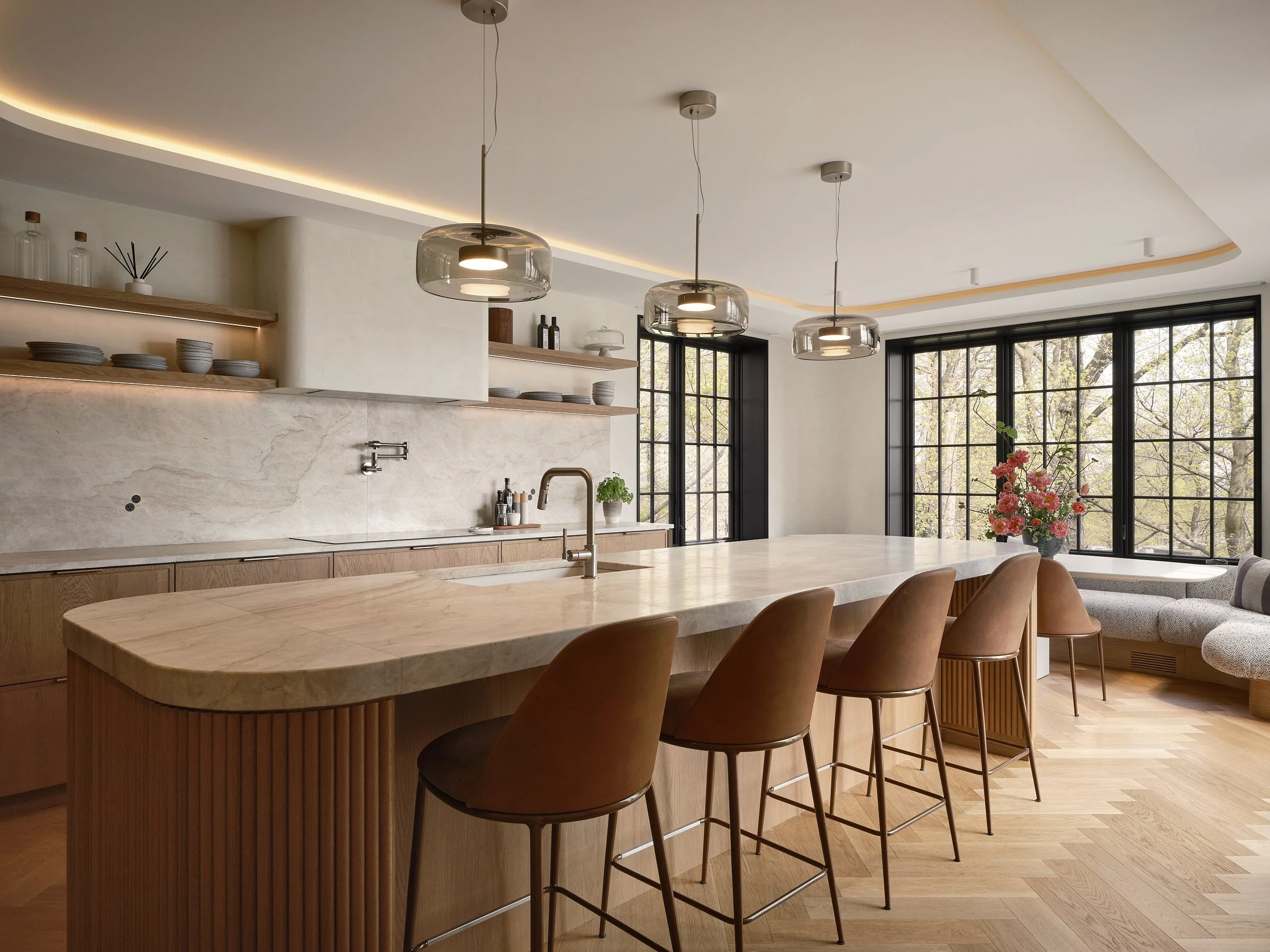 Cuisine sur mesure à Westmount avec grand îlot en pierre, armoires en bois et banquette intégrée près des fenêtres.