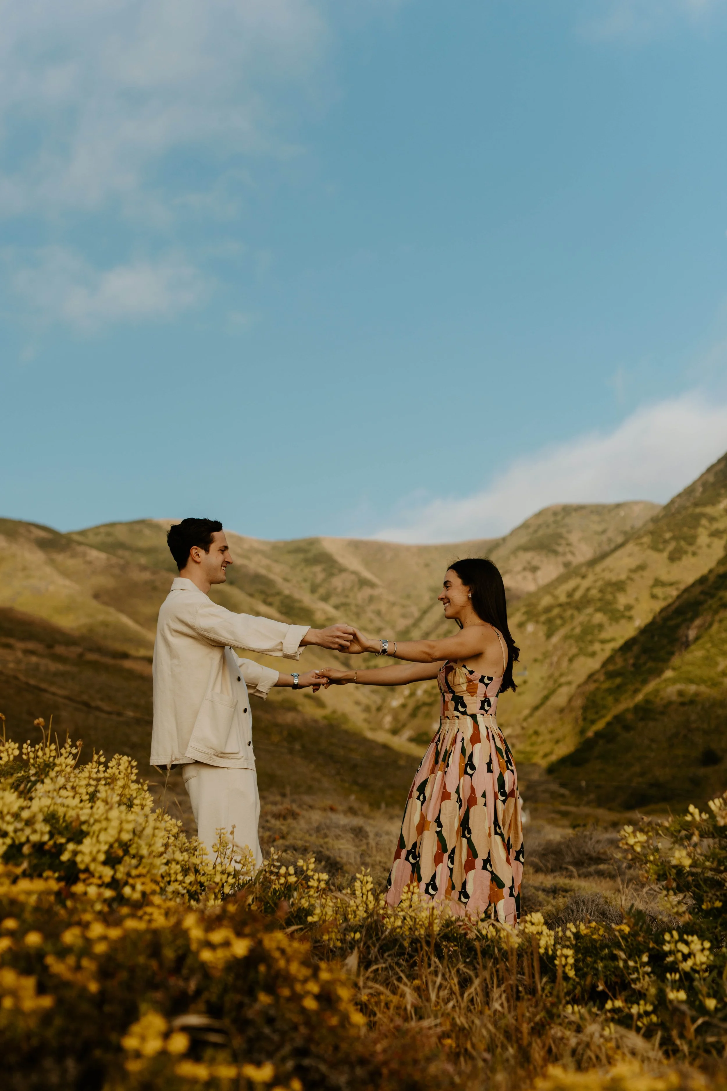 couple holding hands in carmel by the sea mountains during their engagement couples photography session