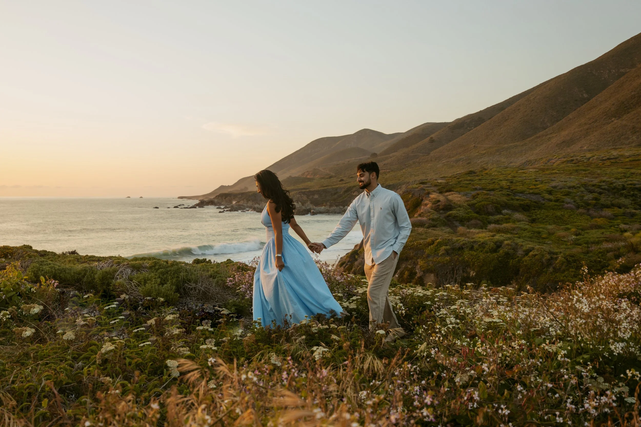 man and woman froliking on Big Sur clifside after proposal in big sur